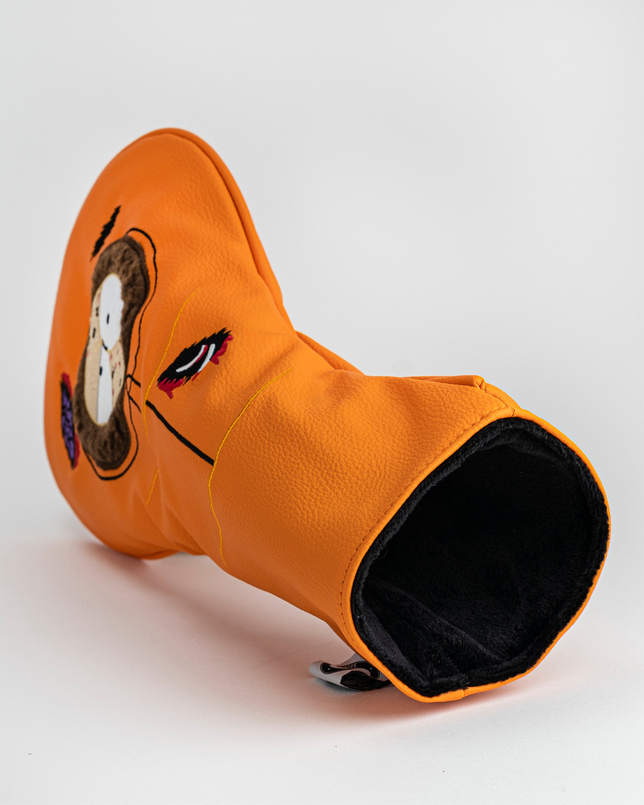 Bright orange golf club headcover with a cartoon dog's face and colorful eye details, designed for bold, standout style.