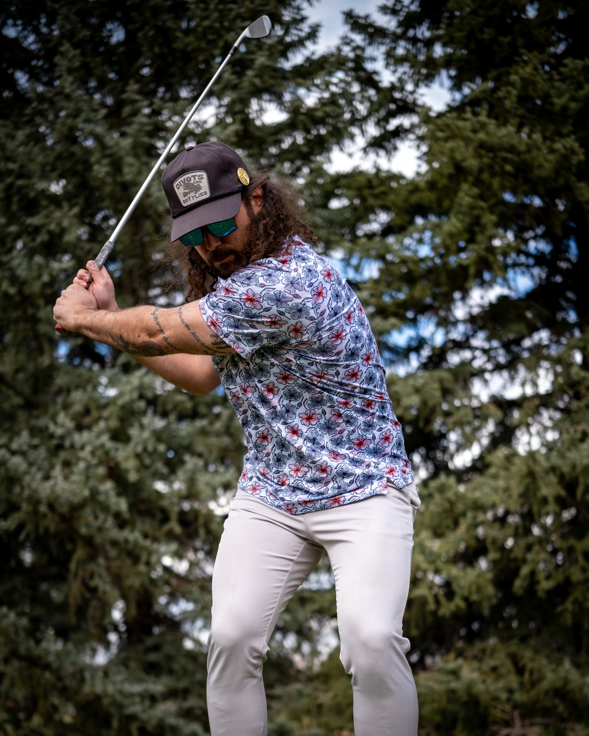 Hibiscus Harmony floral arrangement in a stylish white vase, featuring vibrant hibiscus flowers and greenery, set on a wooden table in a bright, airy room.