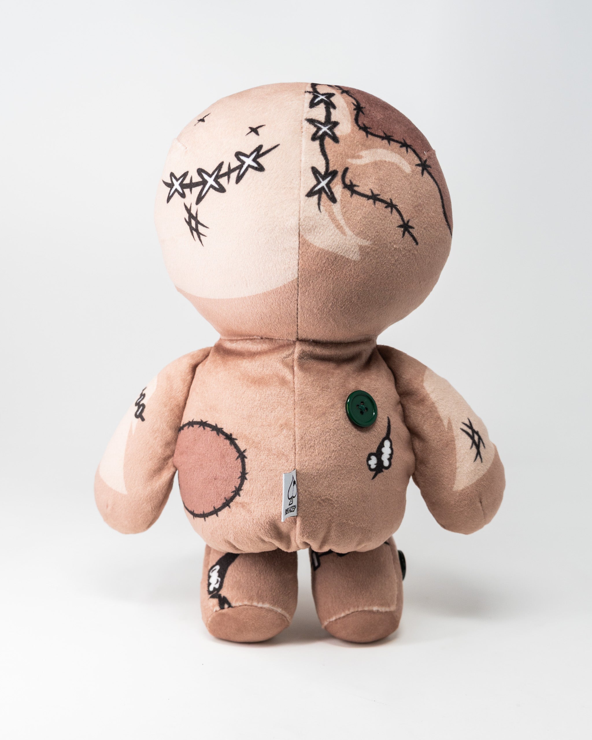 Soft plush voodoo doll-themed driver cover with stitched details, a green button, and a small tag, designed for golf clubs.