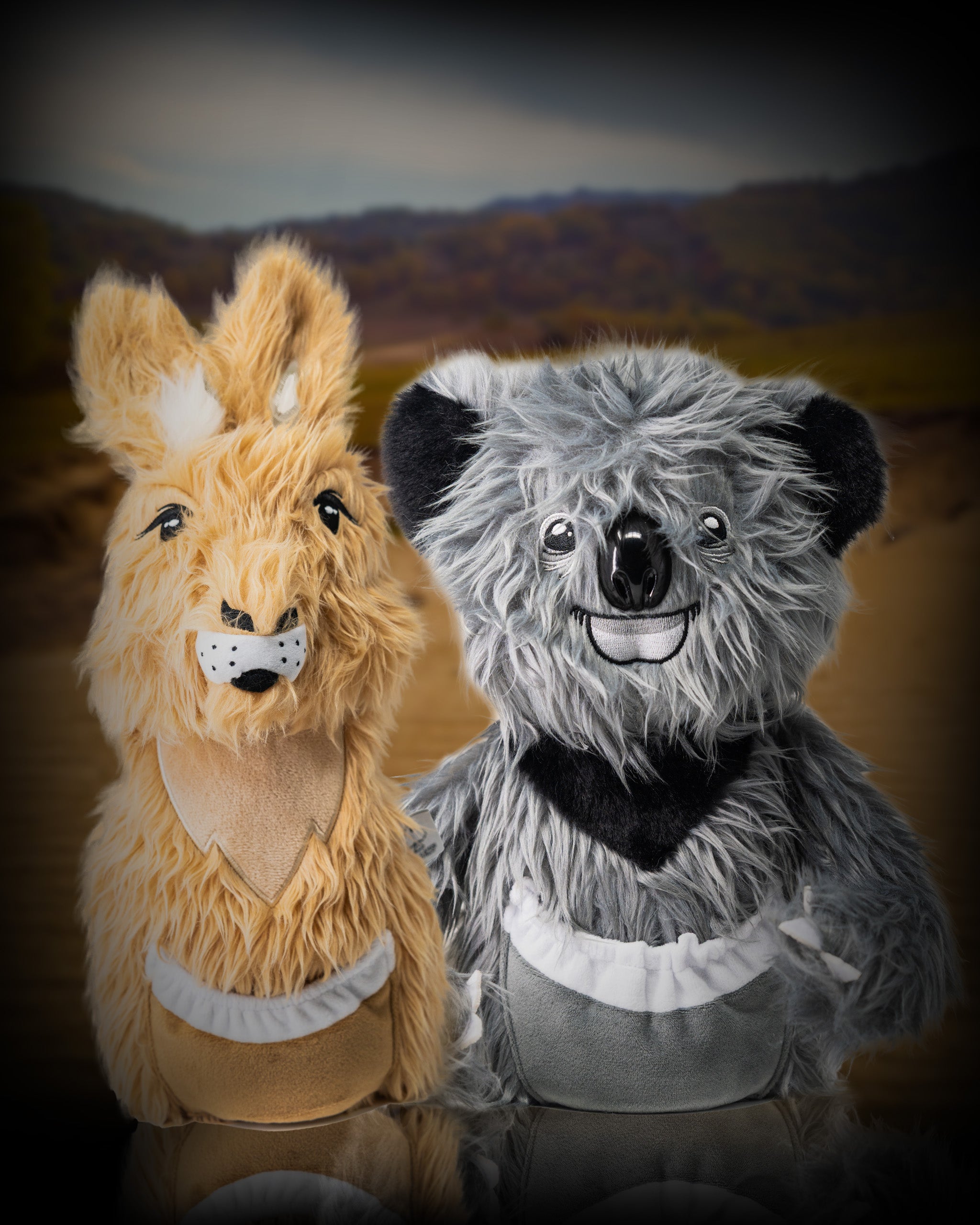 Soft plush koala and kangaroo driver covers with detailed facial features, set against a blurred outdoor landscape background.