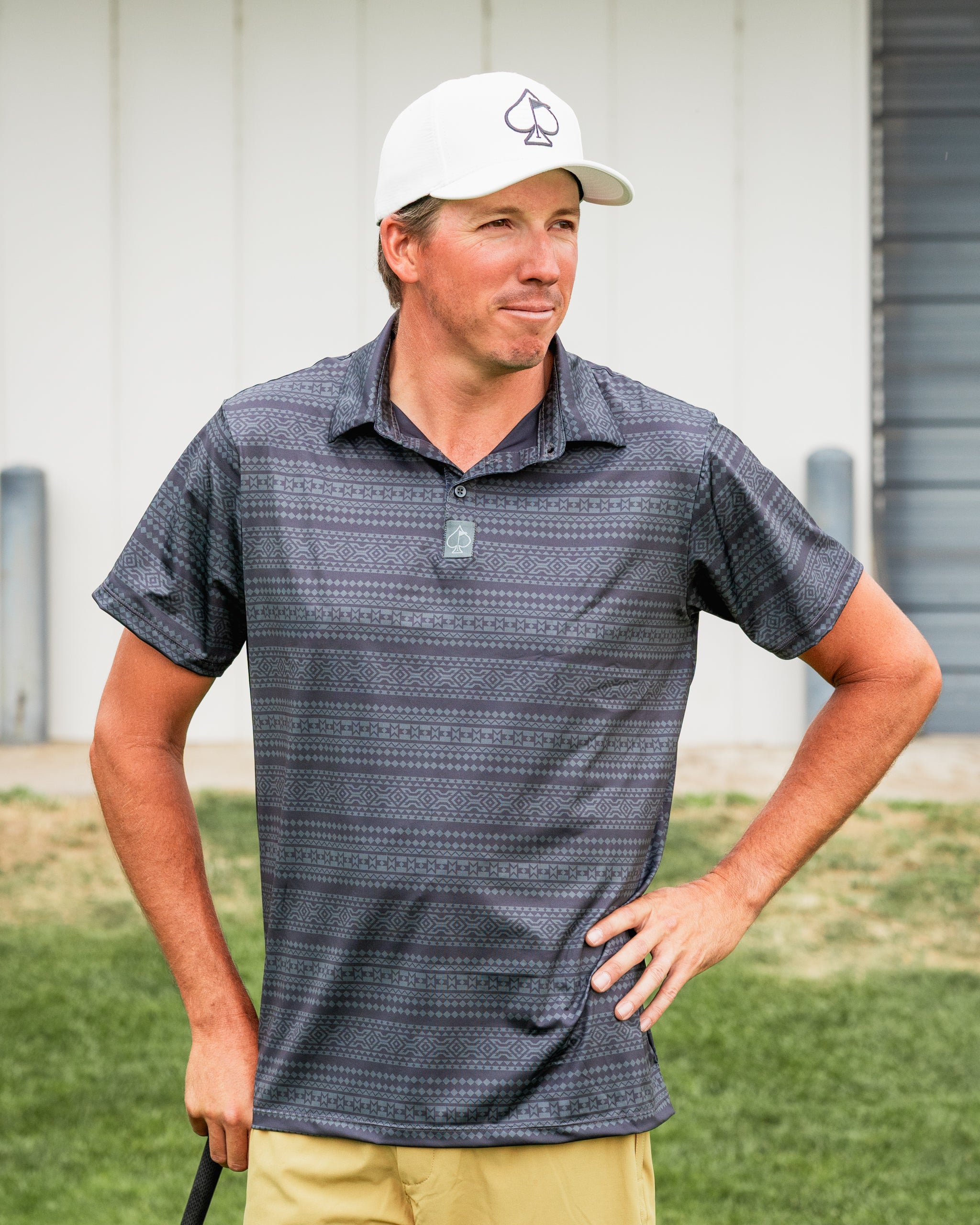 Man wearing a Desert Geo golf polo shirt with a geometric pattern, standing confidently on a golf course.