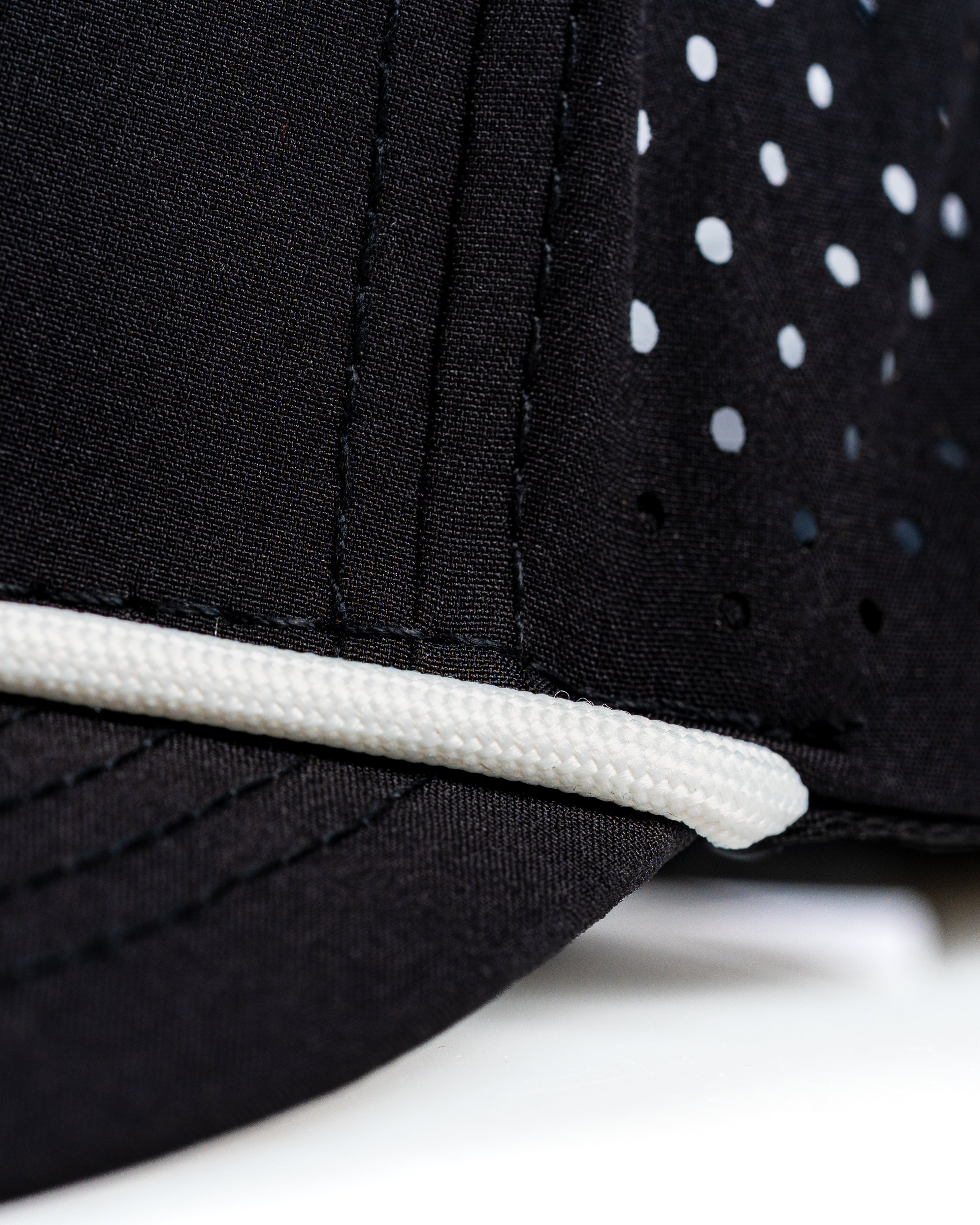 Close-up of the Perforated Rope Hat in black, featuring breathable mesh and a stylish rope detail along the brim.