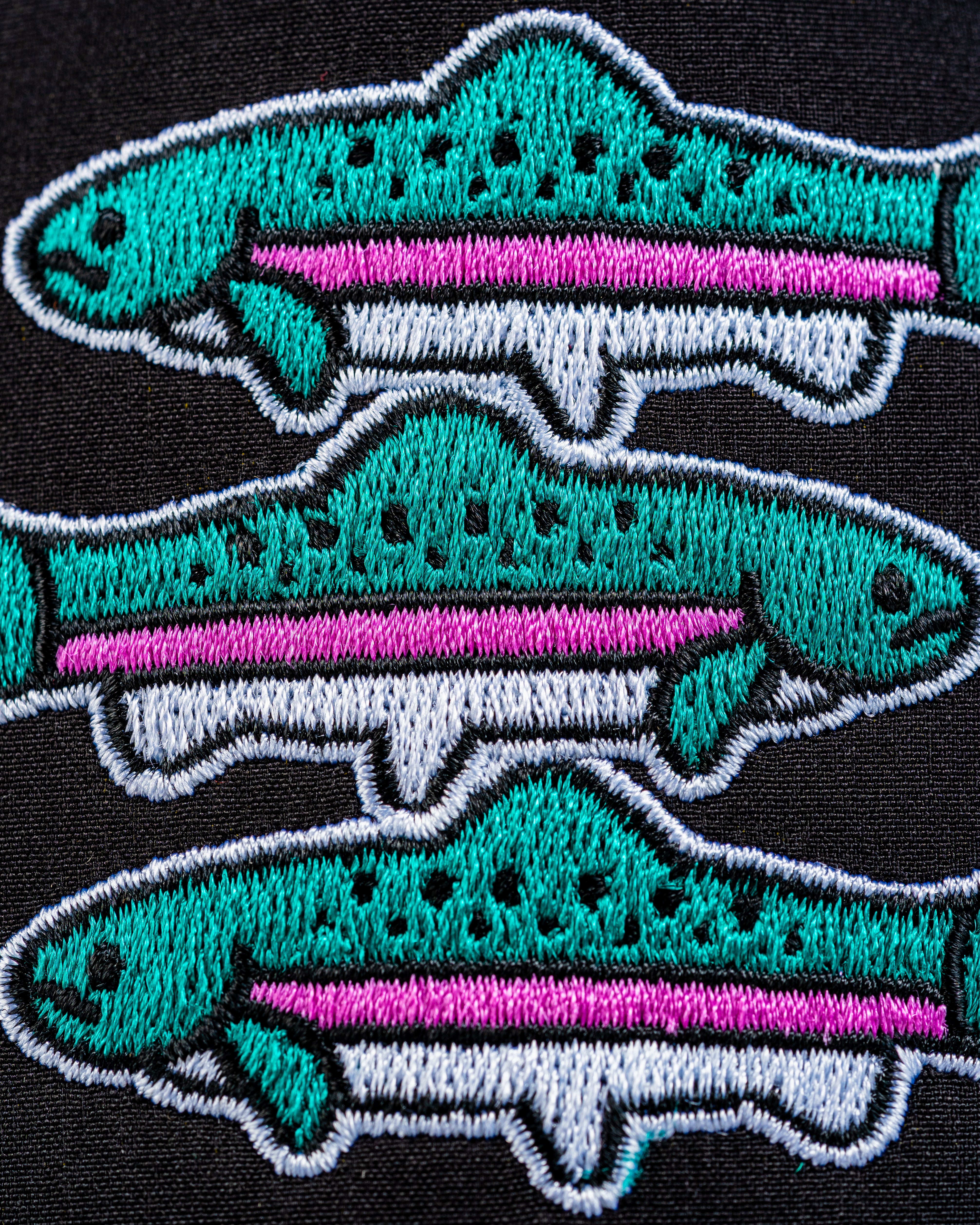 Perforated Rope Hat featuring vibrant embroidered trout designs in teal, pink, and white on a black background.