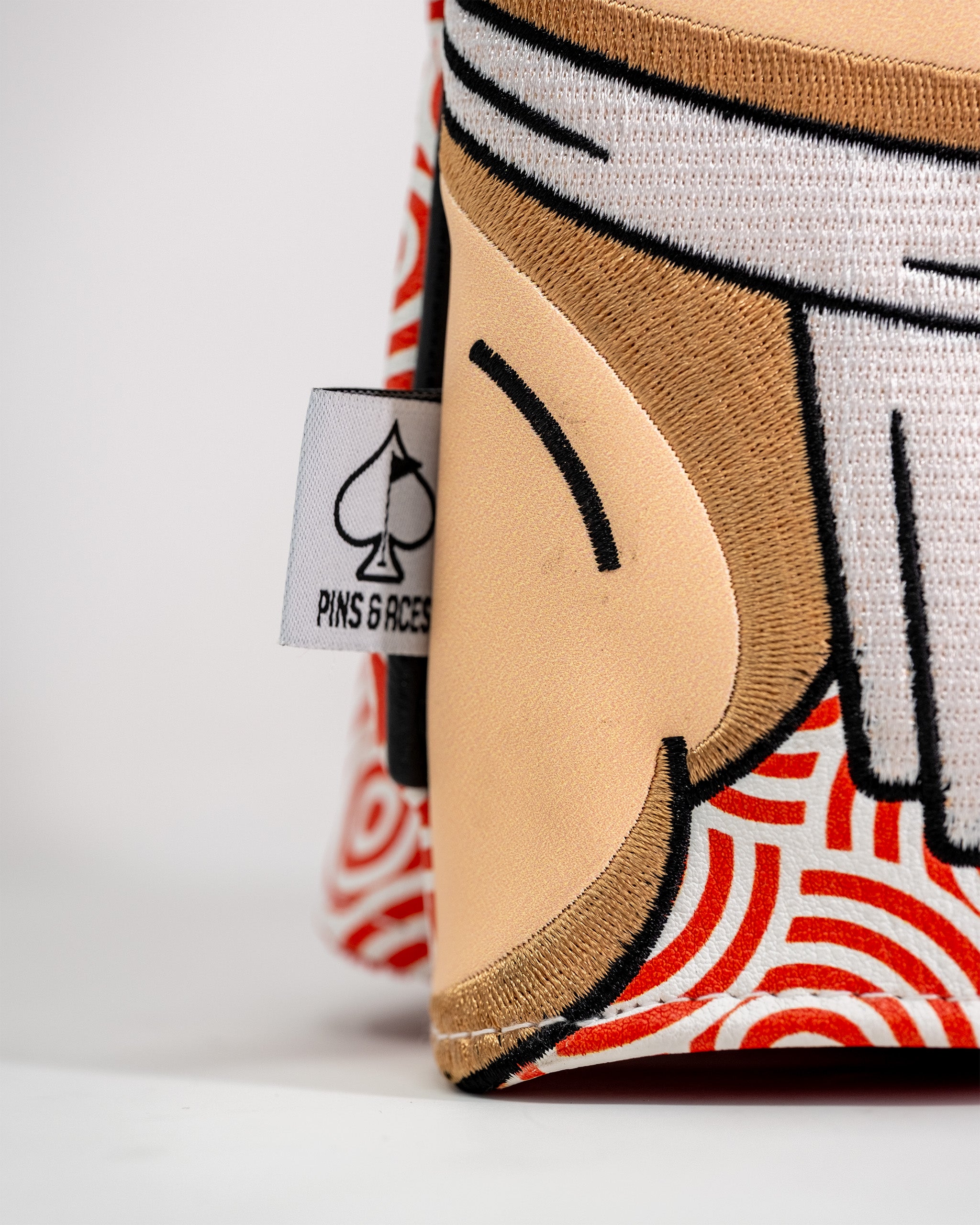 Close-up of a Pins and Aces Sumo driver cover featuring a cartoon face design with a spade logo tag on the side.