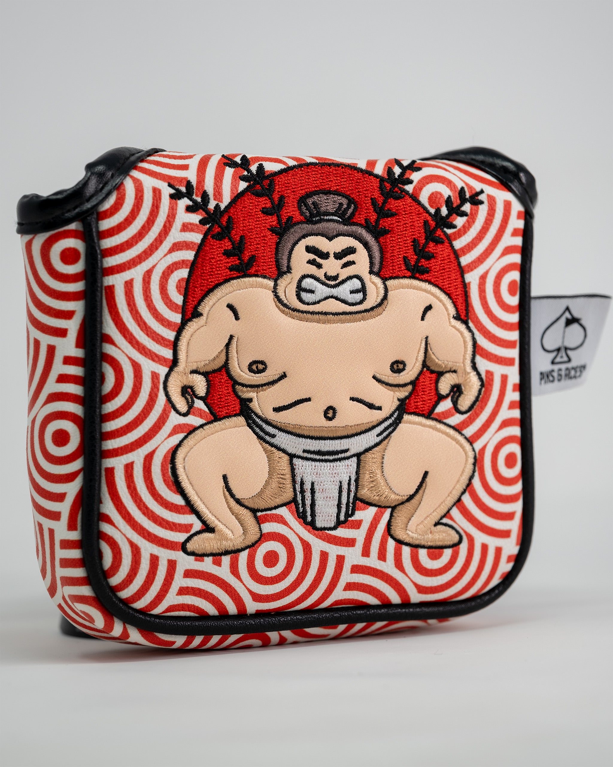 Sumo wrestler embroidered patch on a red and white patterned golf putter cover with black trim.