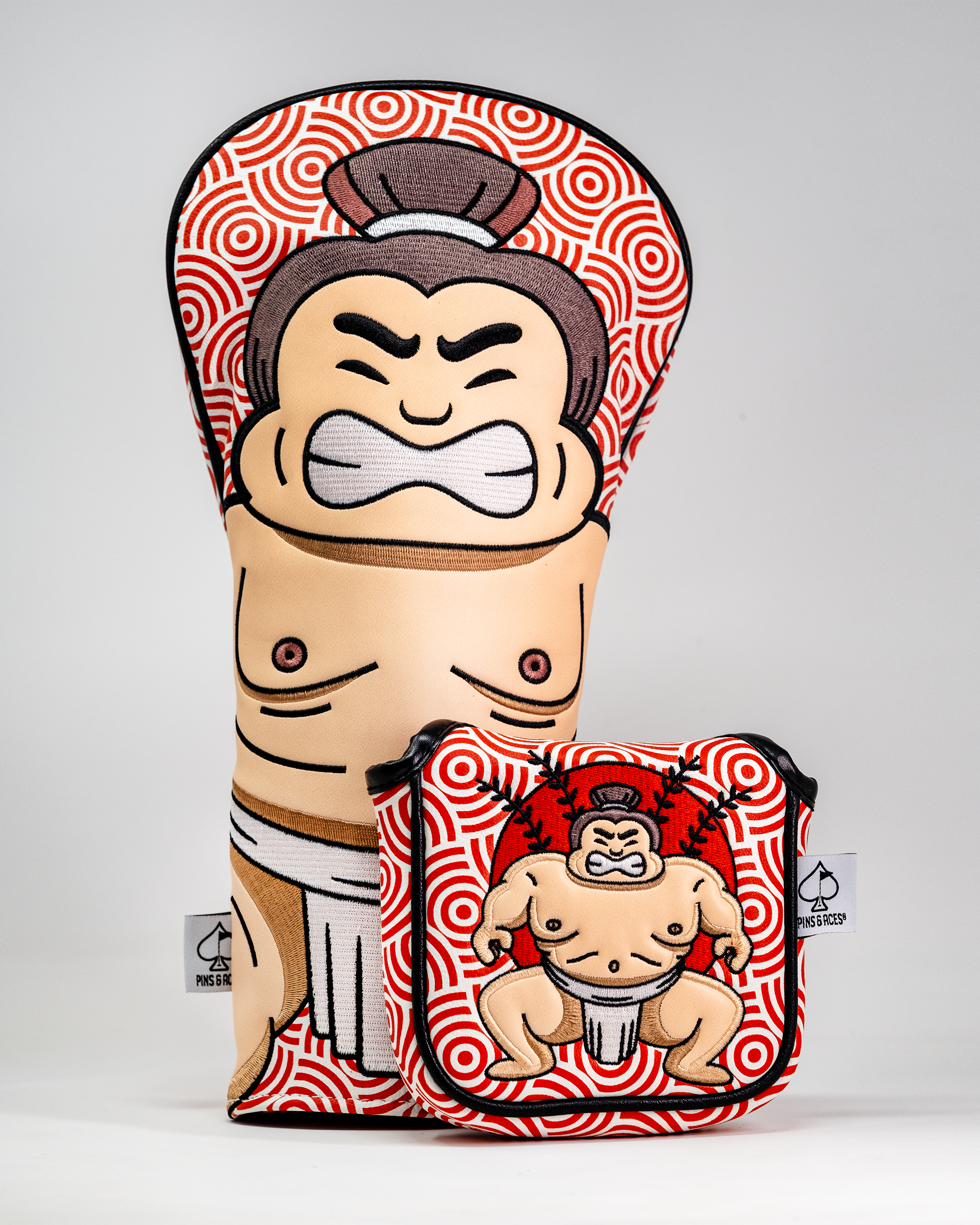 Sumo wrestler-themed driver cover and matching headcover with bold red and white spiral pattern, featuring a cartoon sumo wrestler.