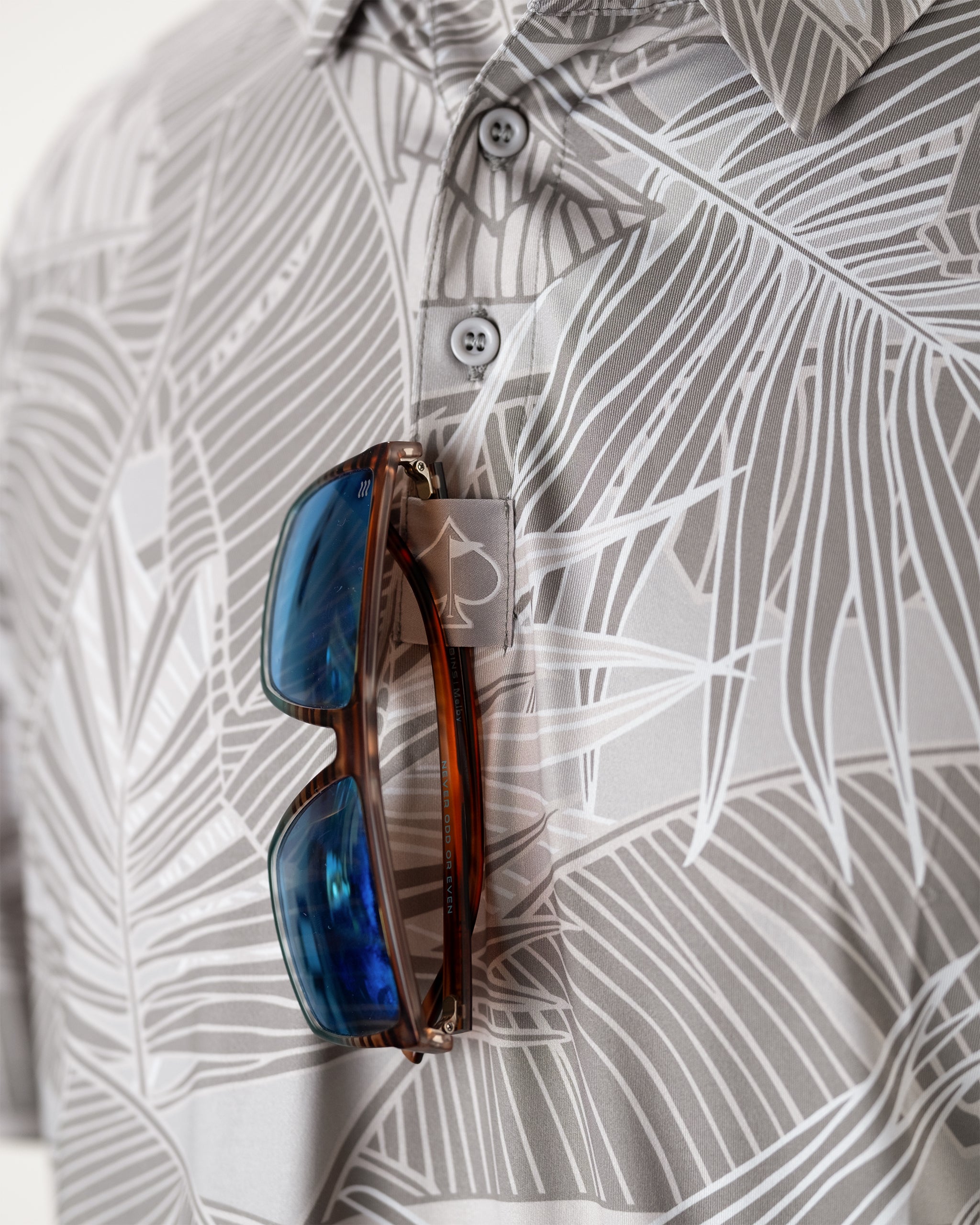 Tropical palm leaves background with a stylish wooden sunglass holder above, featuring circular cutouts for sunglasses.