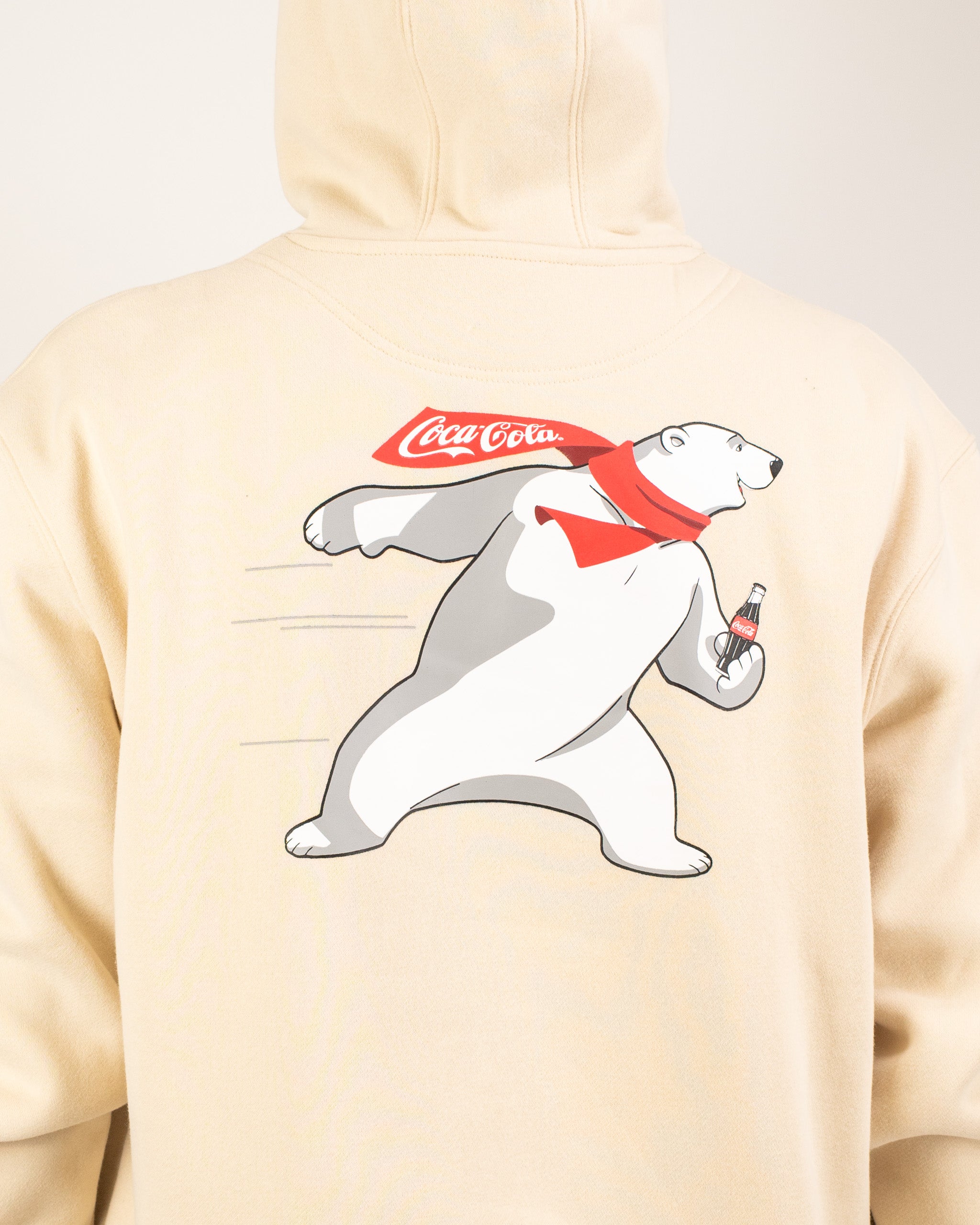 Cream hoodie featuring a playful polar bear graphic holding a Coca-Cola bottle, perfect for casual wear.