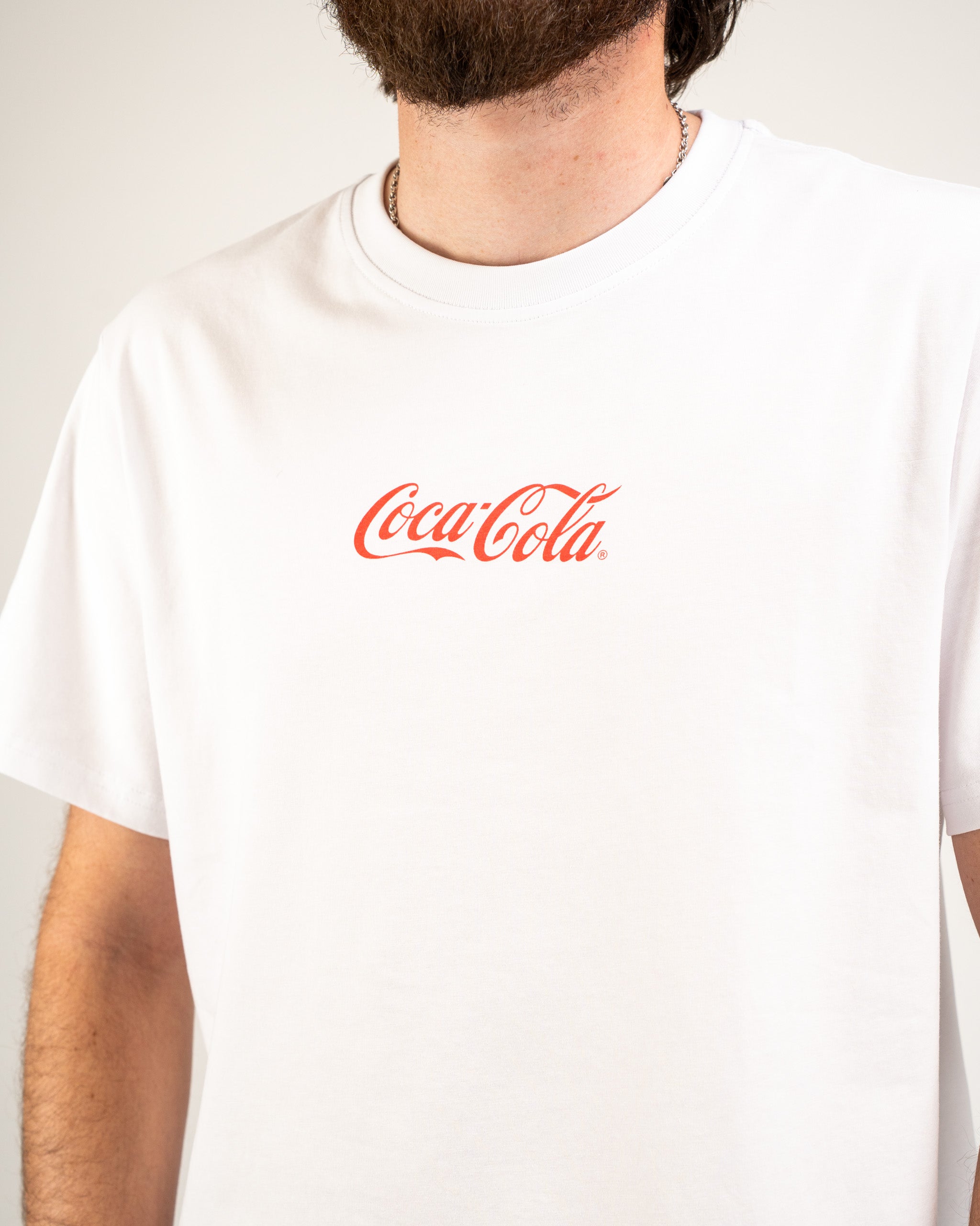 White Coca-Cola tee shirt featuring the iconic red logo, perfect for casual wear and brand enthusiasts.