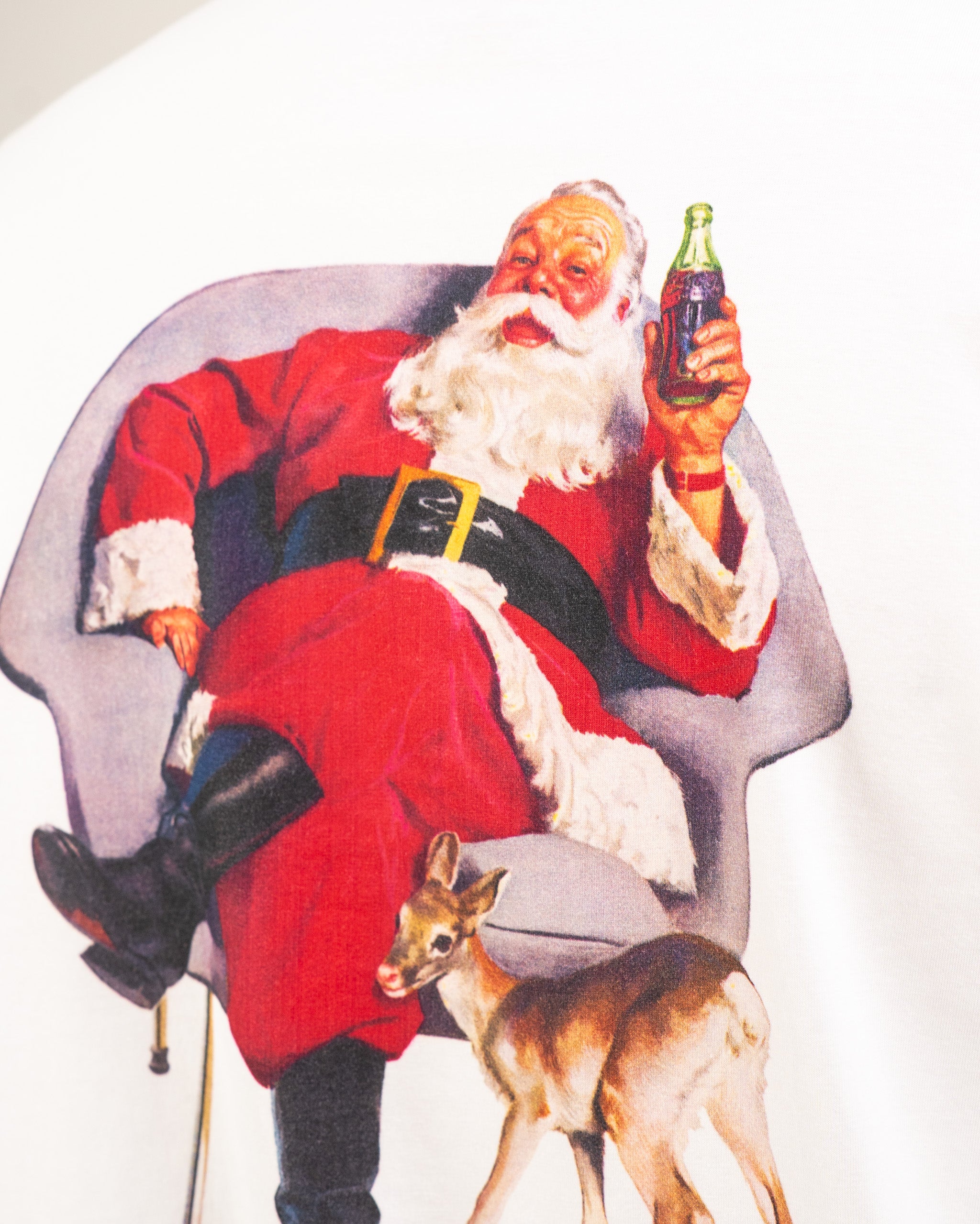 Vintage Coca-Cola White tee shirt featuring Santa Claus holding a Coke, sitting in a chair with a deer at his feet.