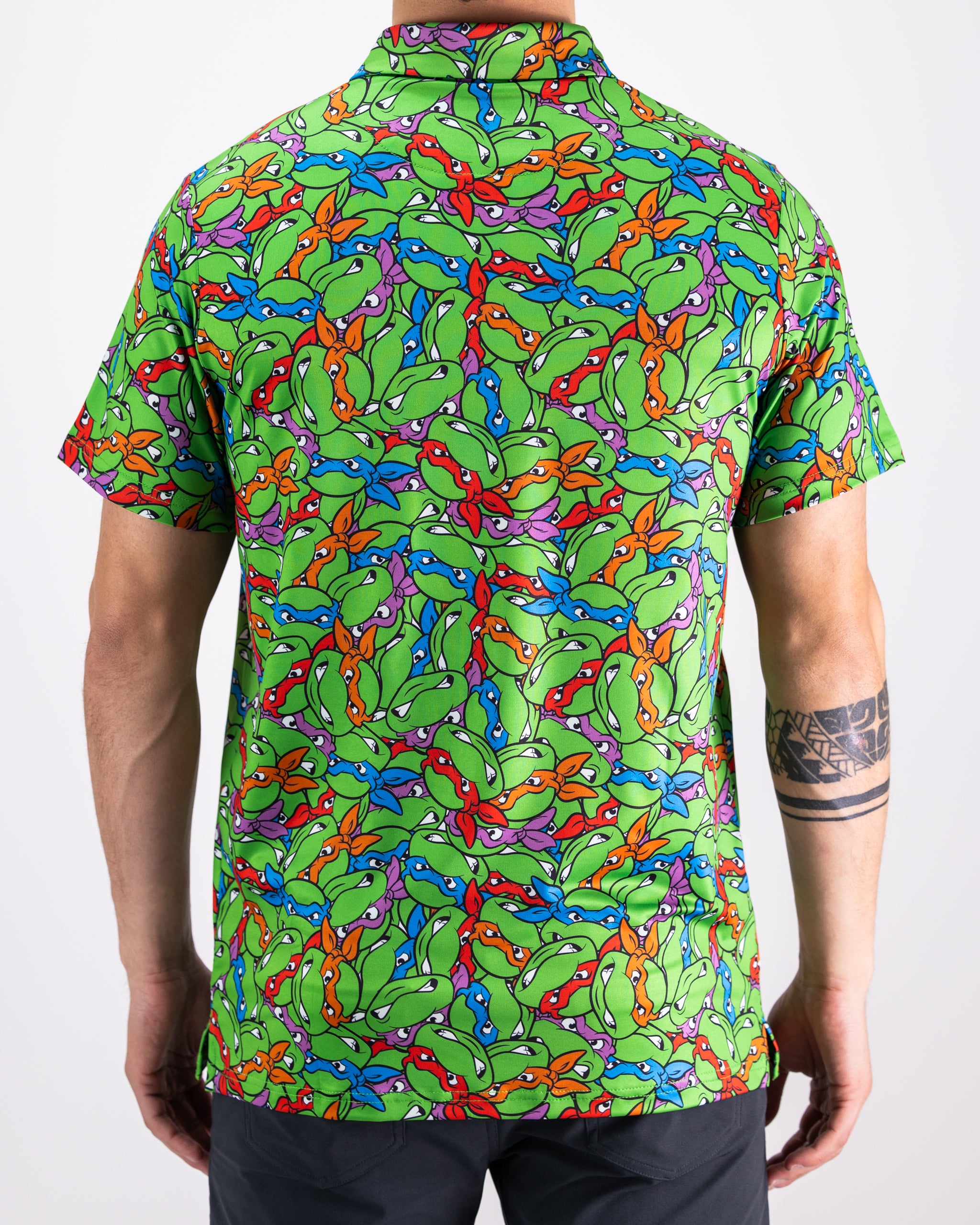 TMNT Mean Green polo shirt featuring colorful turtle head designs on a vibrant green background.