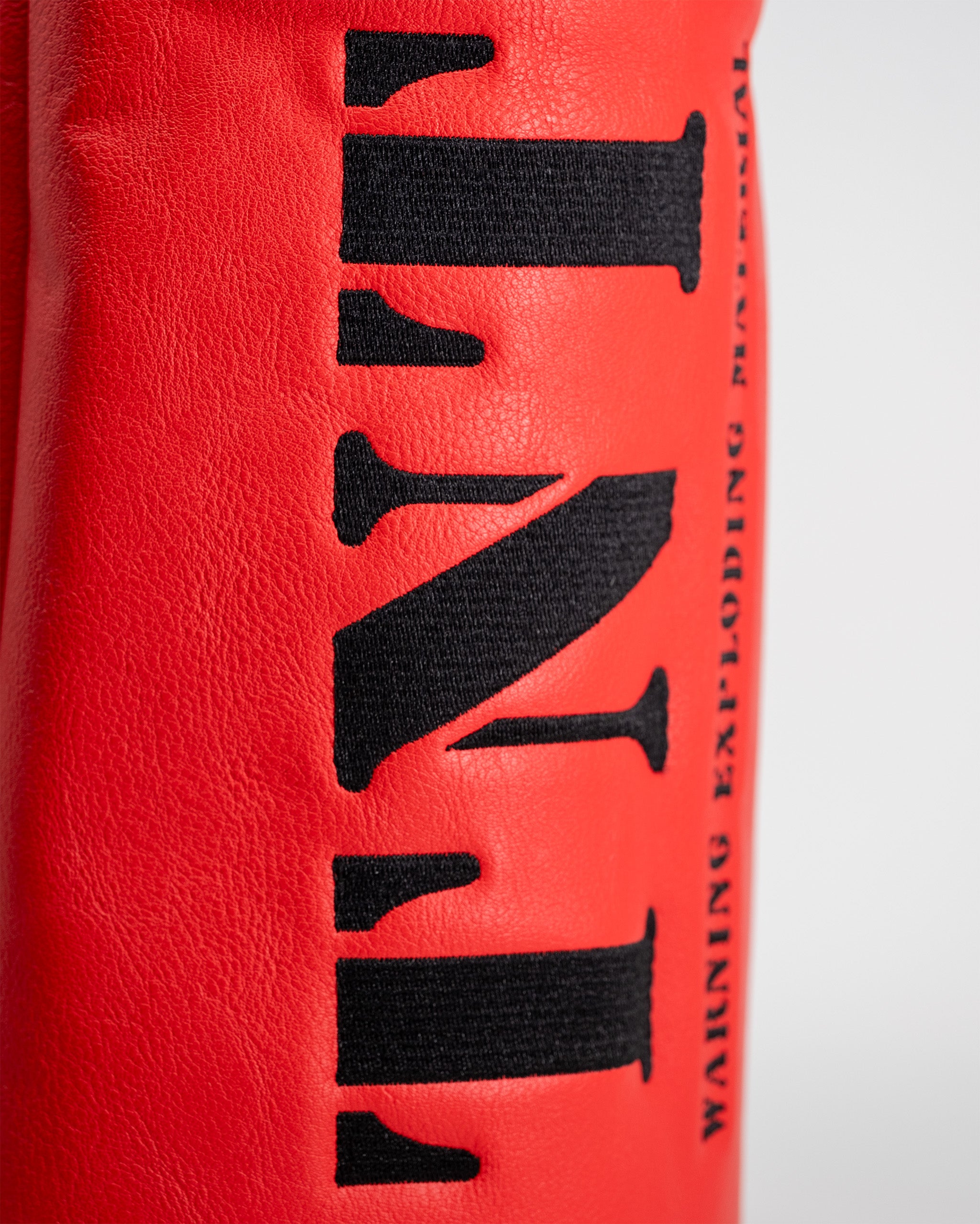 Close-up of a red driver cover with black embroidered text reading "TNT" and additional branding details.