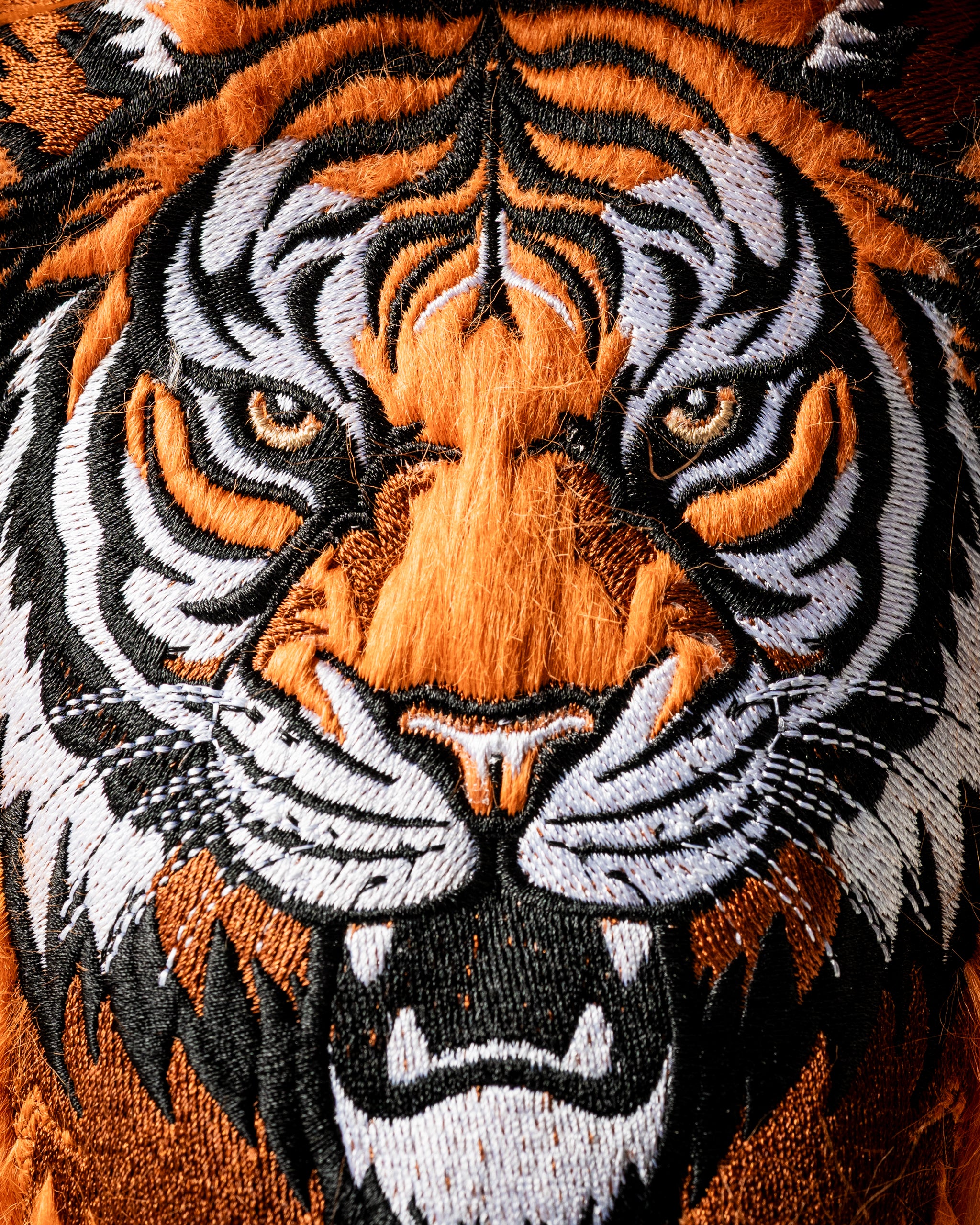 Detailed embroidered tiger face design on a fairway cover, showcasing vibrant orange and black colors for a bold golf accessory.