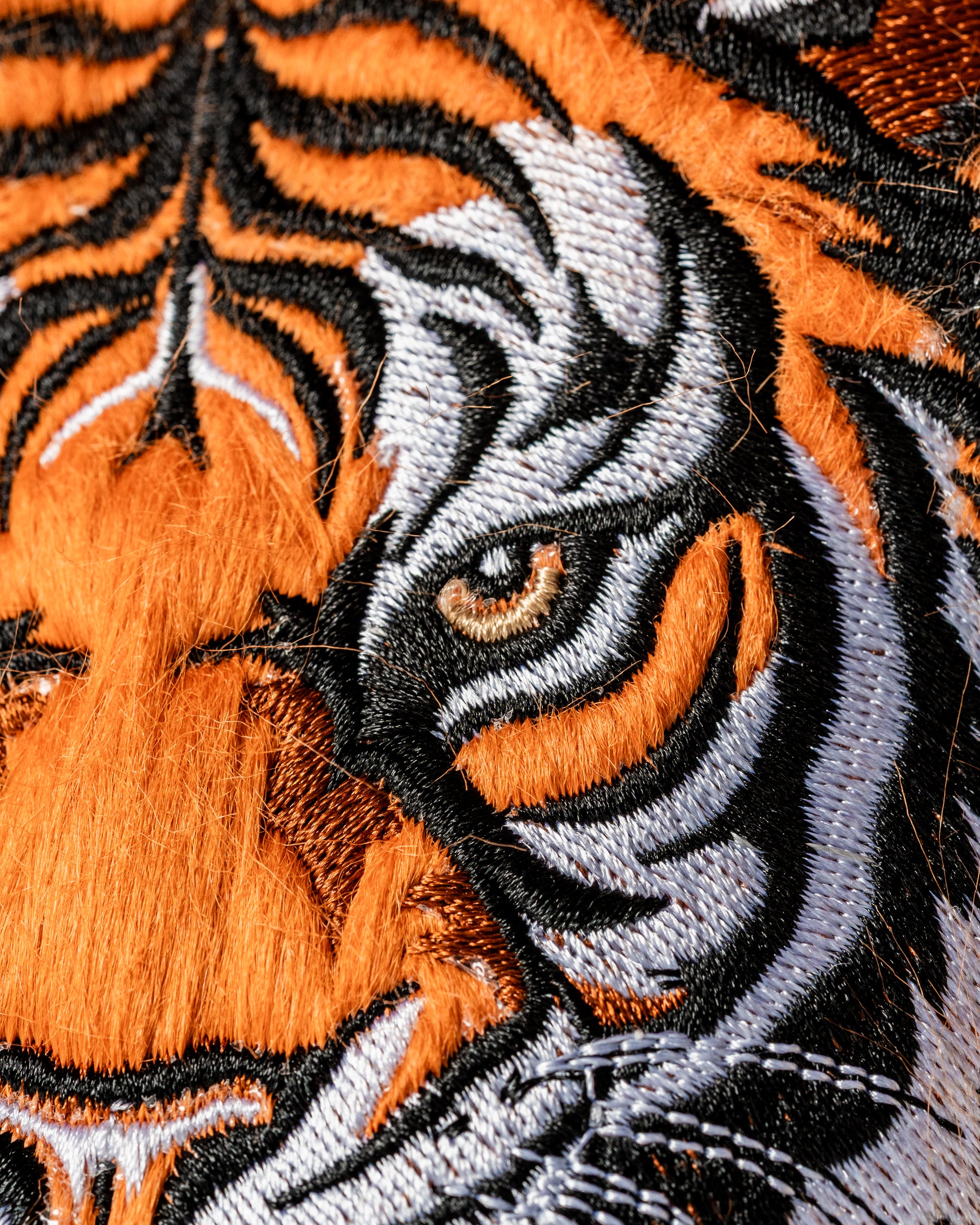 Close-up of a vibrant embroidered tiger face on a fairway cover, showcasing bold orange and black details.