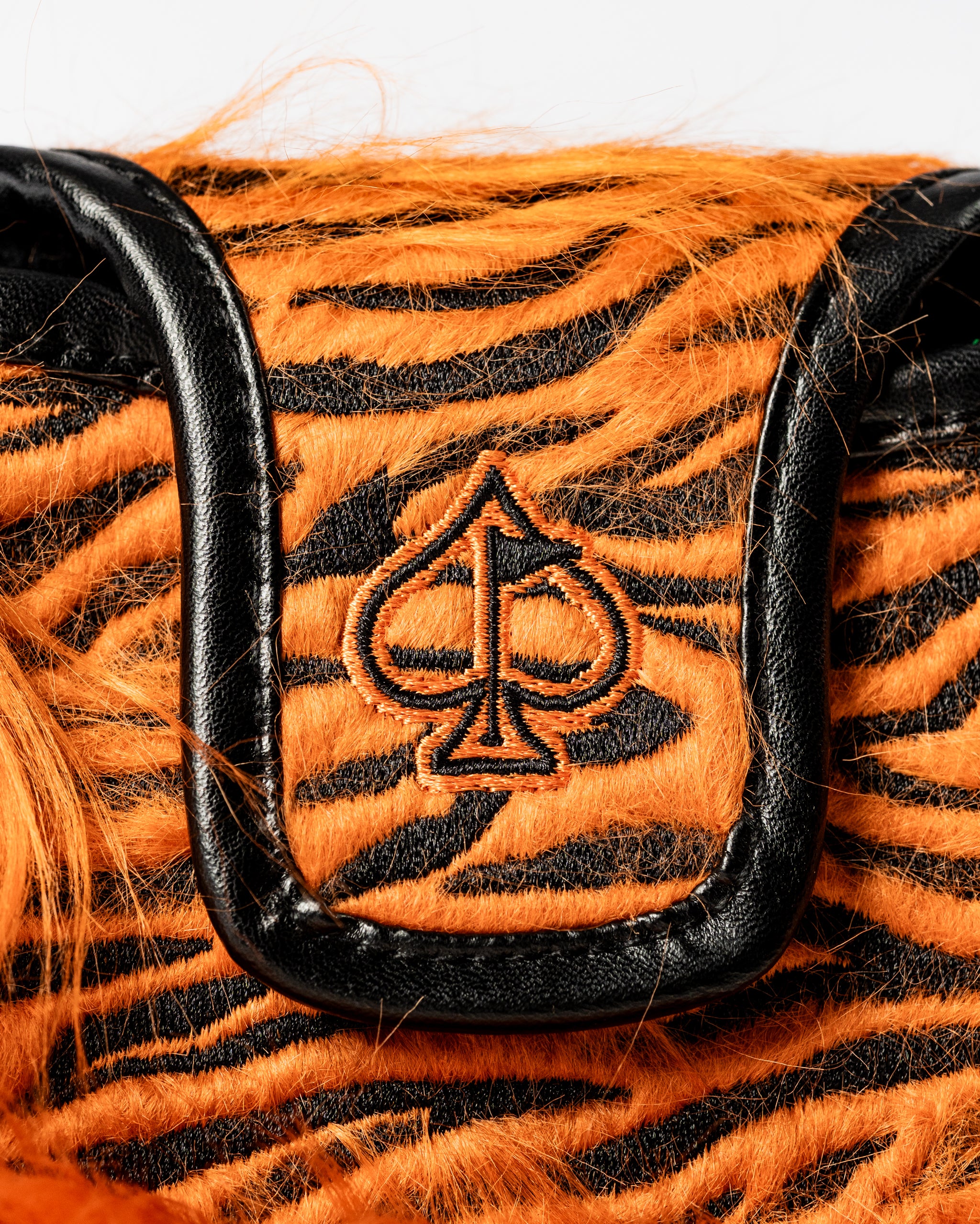 Bold orange and black tiger-striped mallet putter cover featuring a black spade logo, designed for standout golfers.