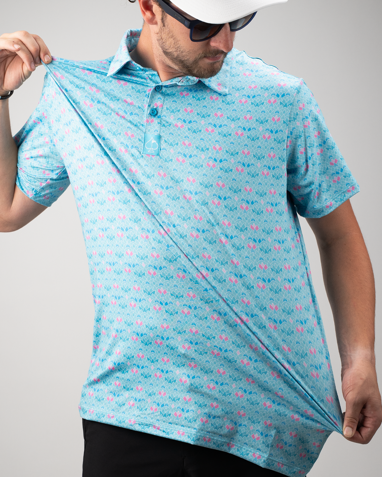 Man showcasing a light blue polo shirt with a vibrant triangle bloom pattern, featuring pink and purple accents.