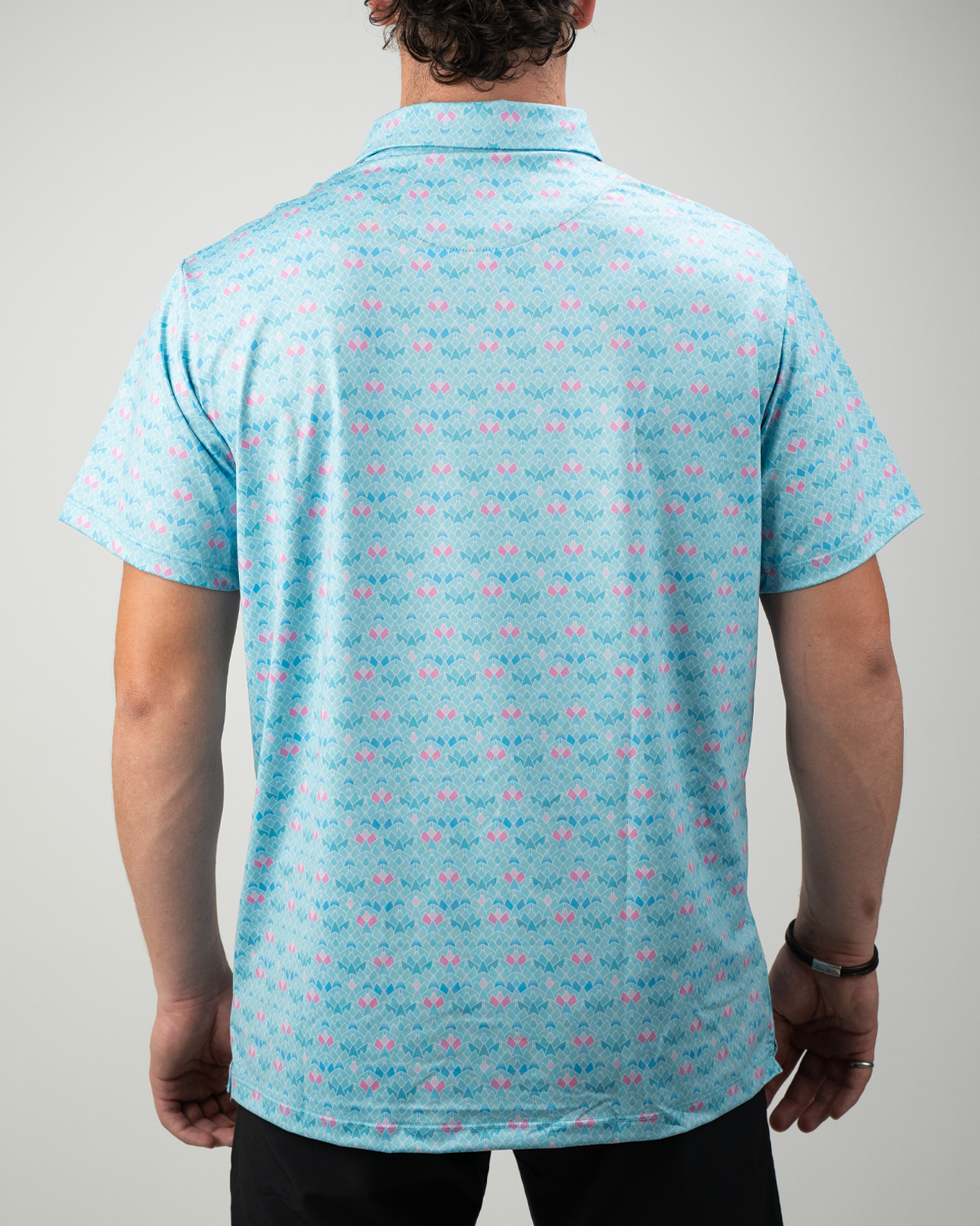 Men's golf polo shirt featuring a vibrant triangle bloom pattern in shades of pink and blue, designed for a stylish look on the course.