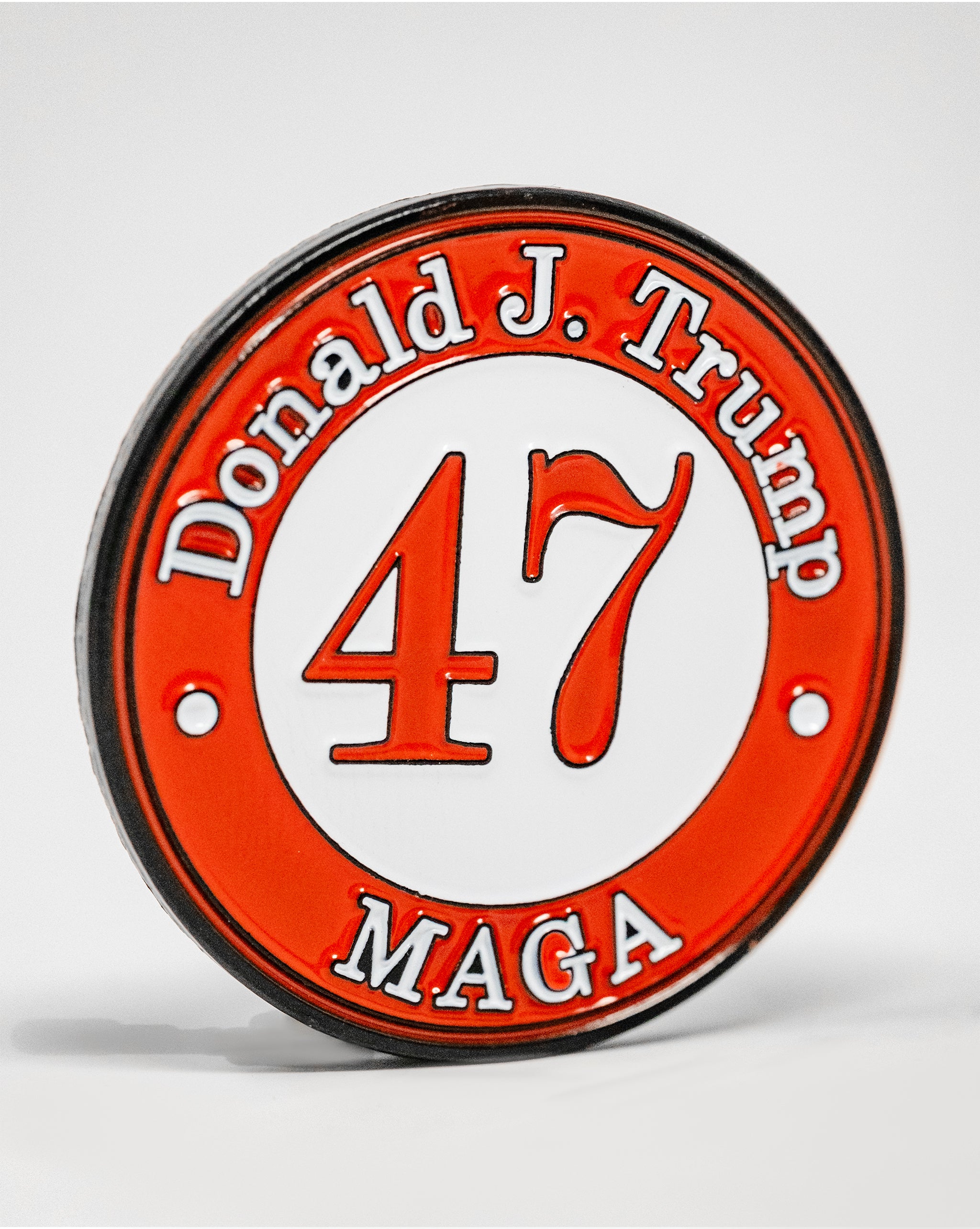 Red and white golf ball marker featuring "Donald J. Trump," the number "47," and "MAGA" in bold lettering.