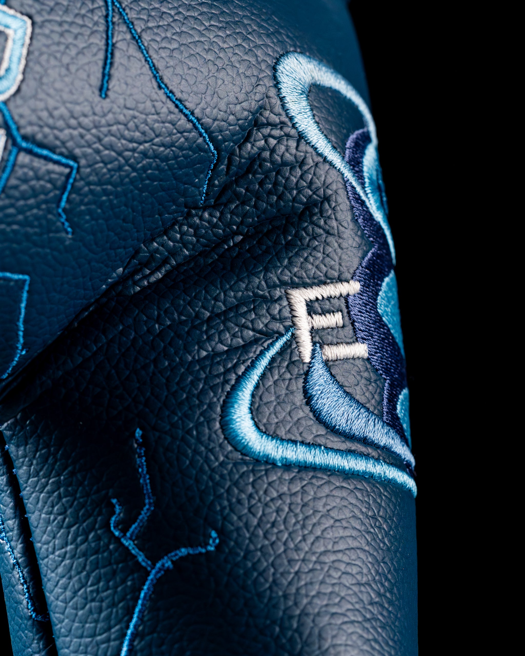 Close-up of the Edel Twister Putter headcover featuring intricate blue and white embroidery on textured leather.