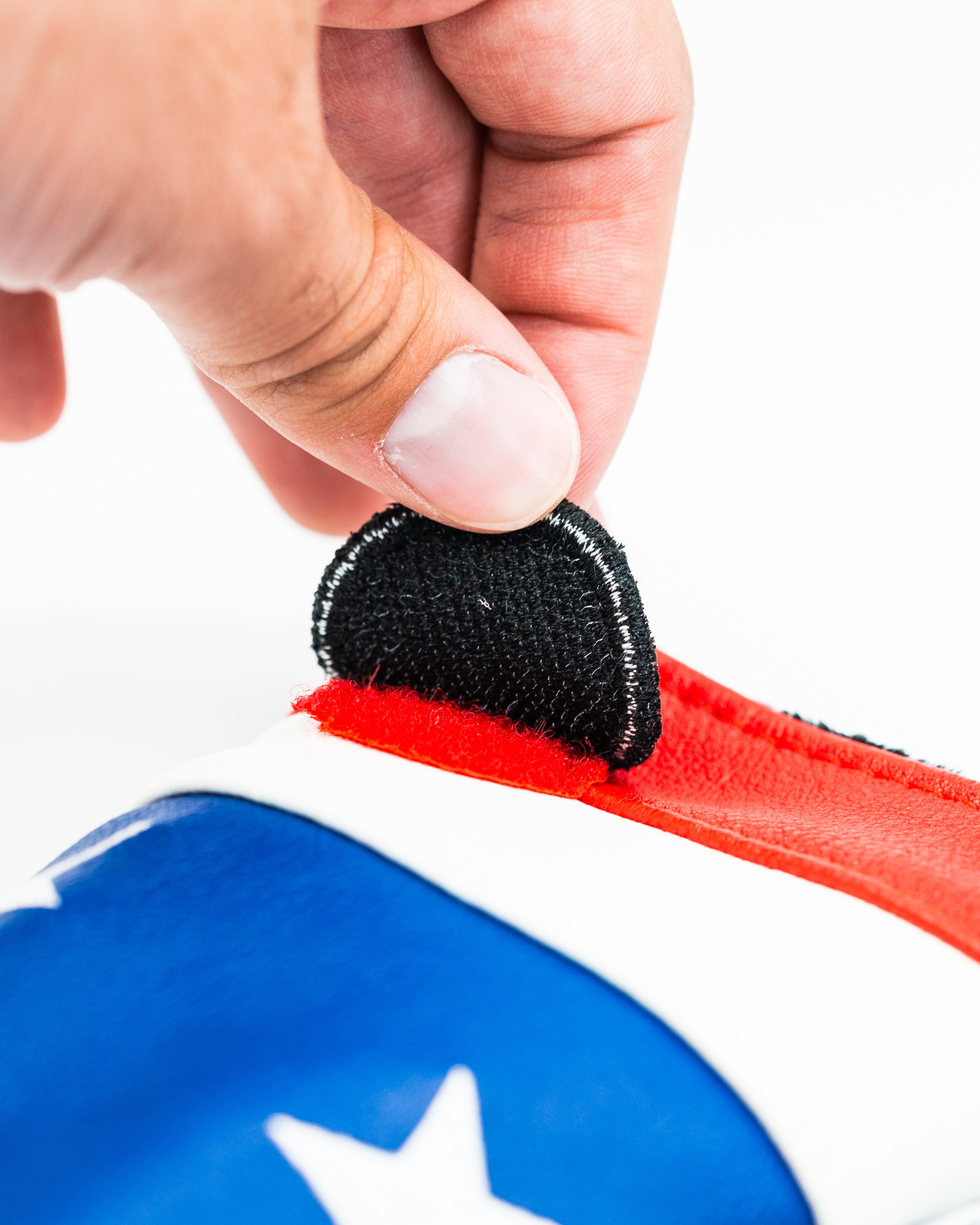 Black headcover patch being attached to a colorful golf headcover, showcasing its secure Velcro design.