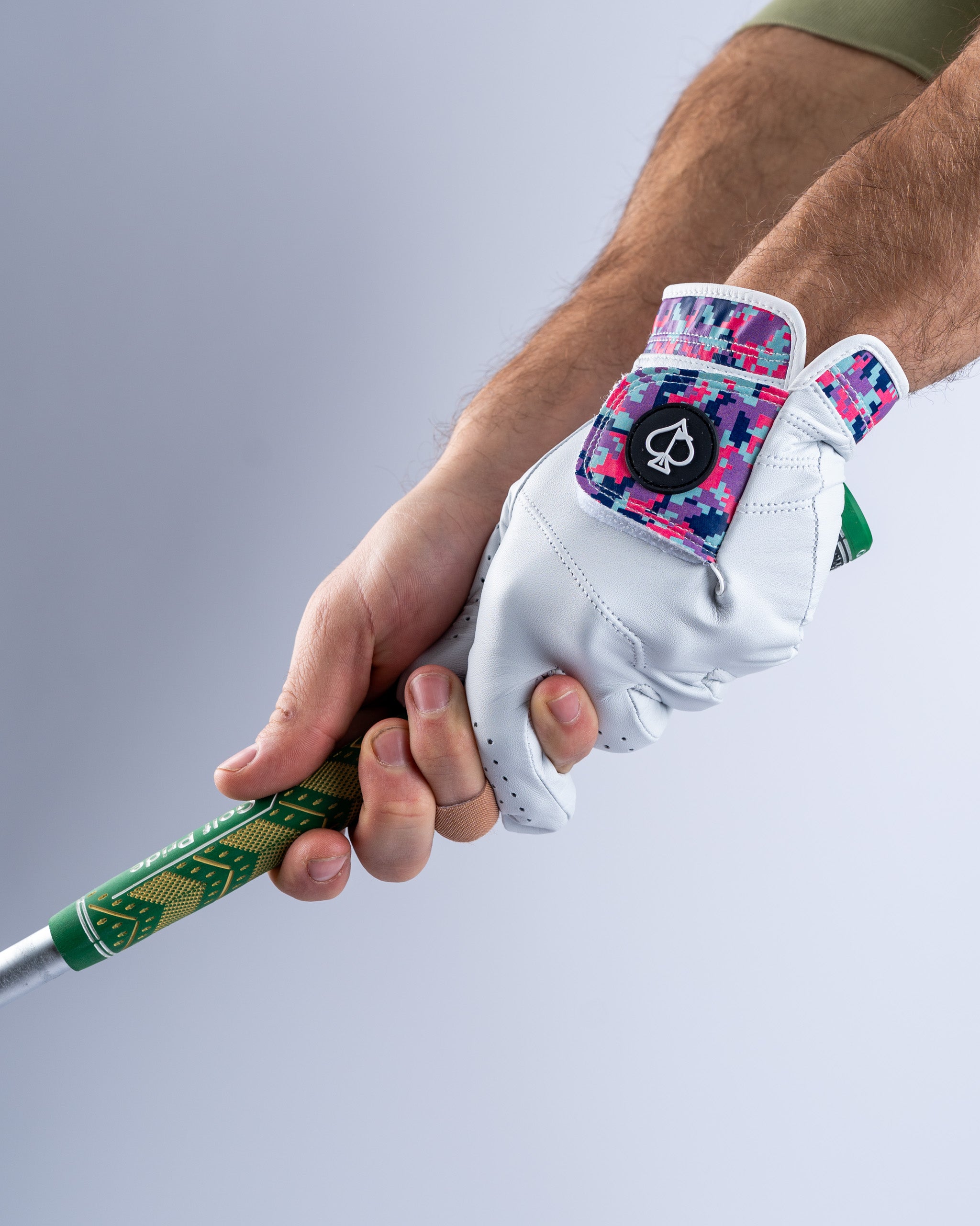 Premium Tour Glove in vivid camo design, featuring a white leather finish and colorful accents, gripping a golf club.