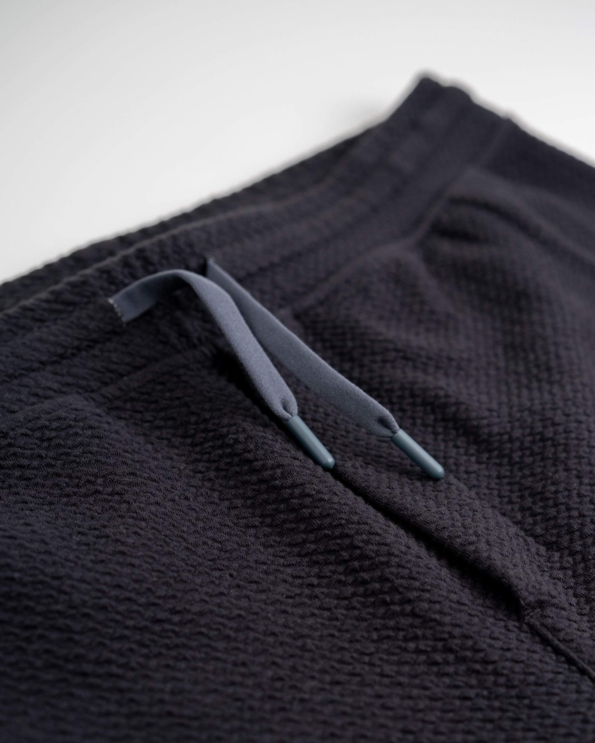 Close-up of black textured golf shorts with gray drawstrings, perfect for bold, standout golf apparel.