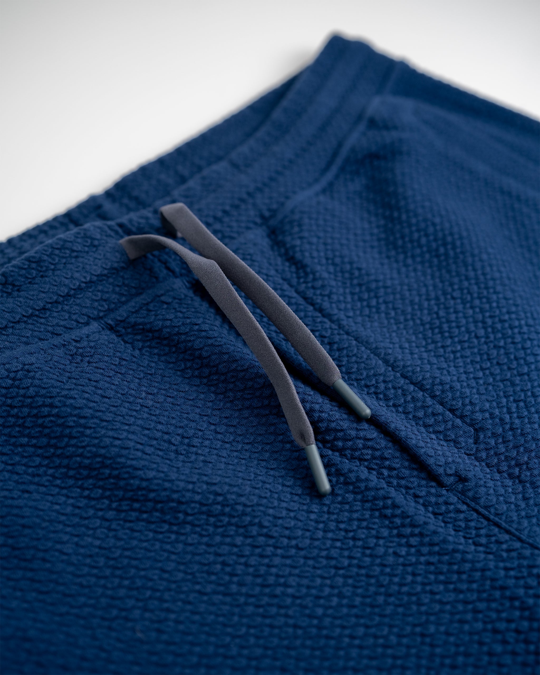 Close-up of navy textured golf pants with gray drawstring, highlighting bold, unique golf apparel for stand-out players.