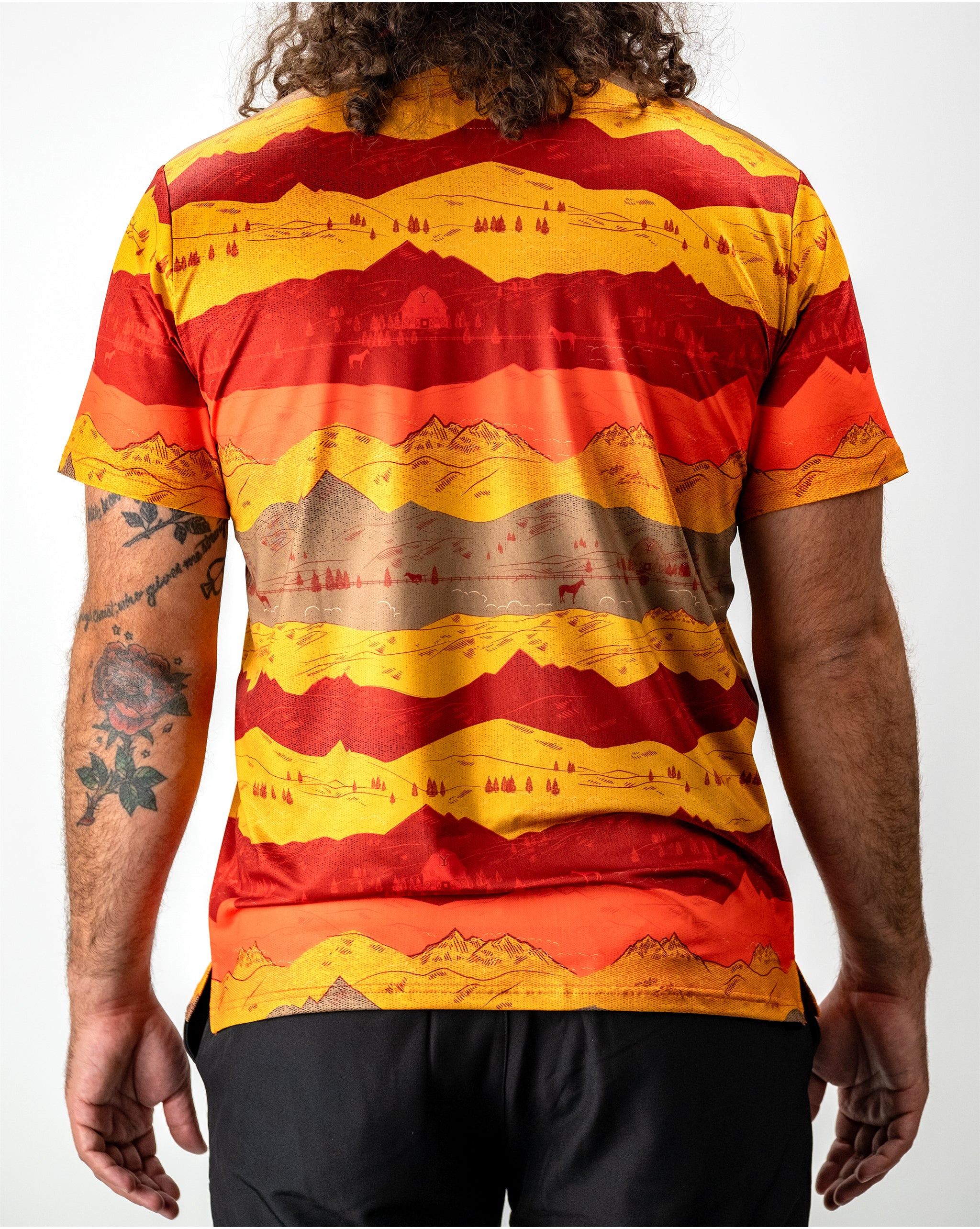 Sunset over Yellowstone National Park, showcasing vibrant orange and purple hues in the sky above scenic mountains and trees.