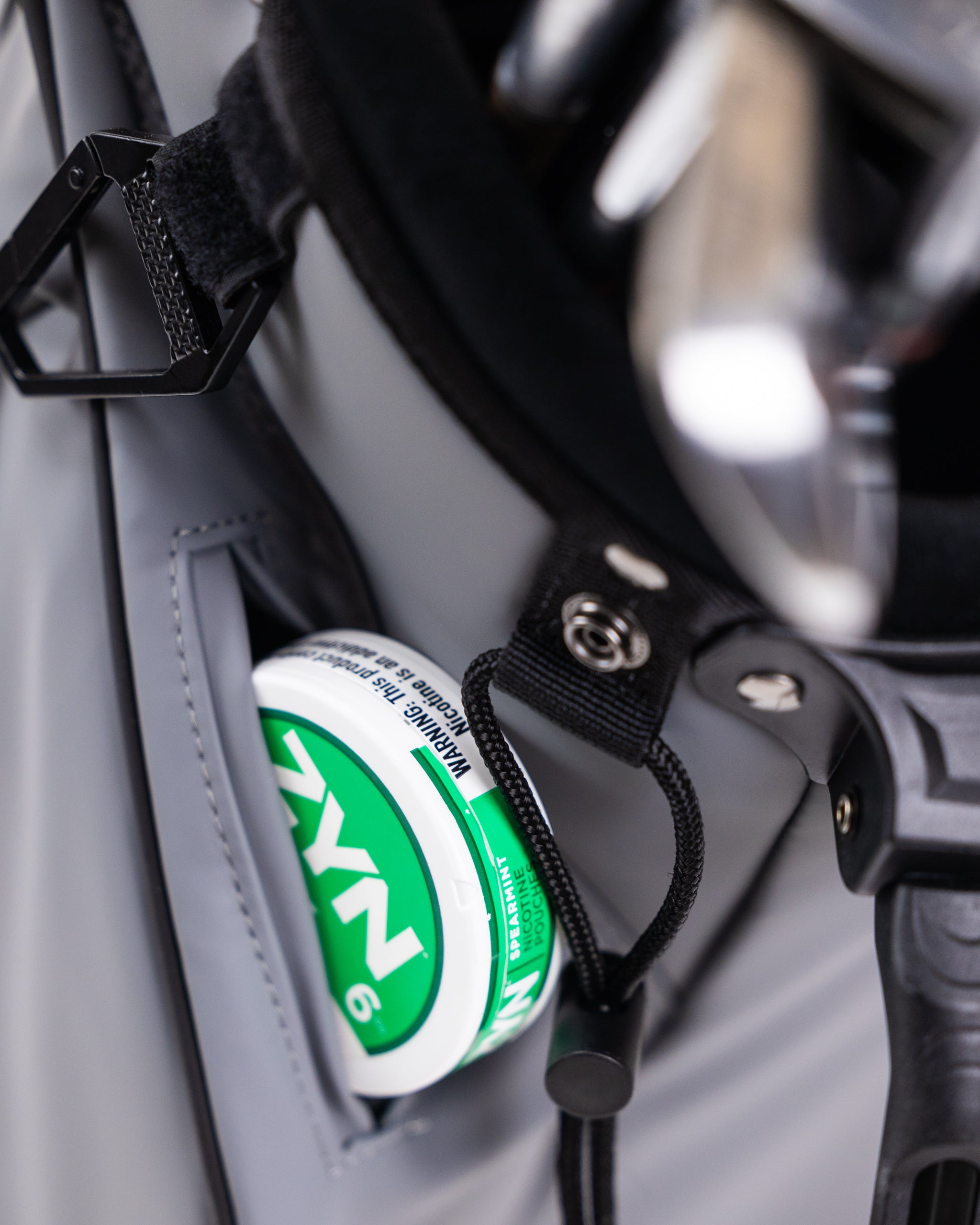 Close-up of golf accessories with a bold green and white canister secured in a pocket on a sleek golf cart.