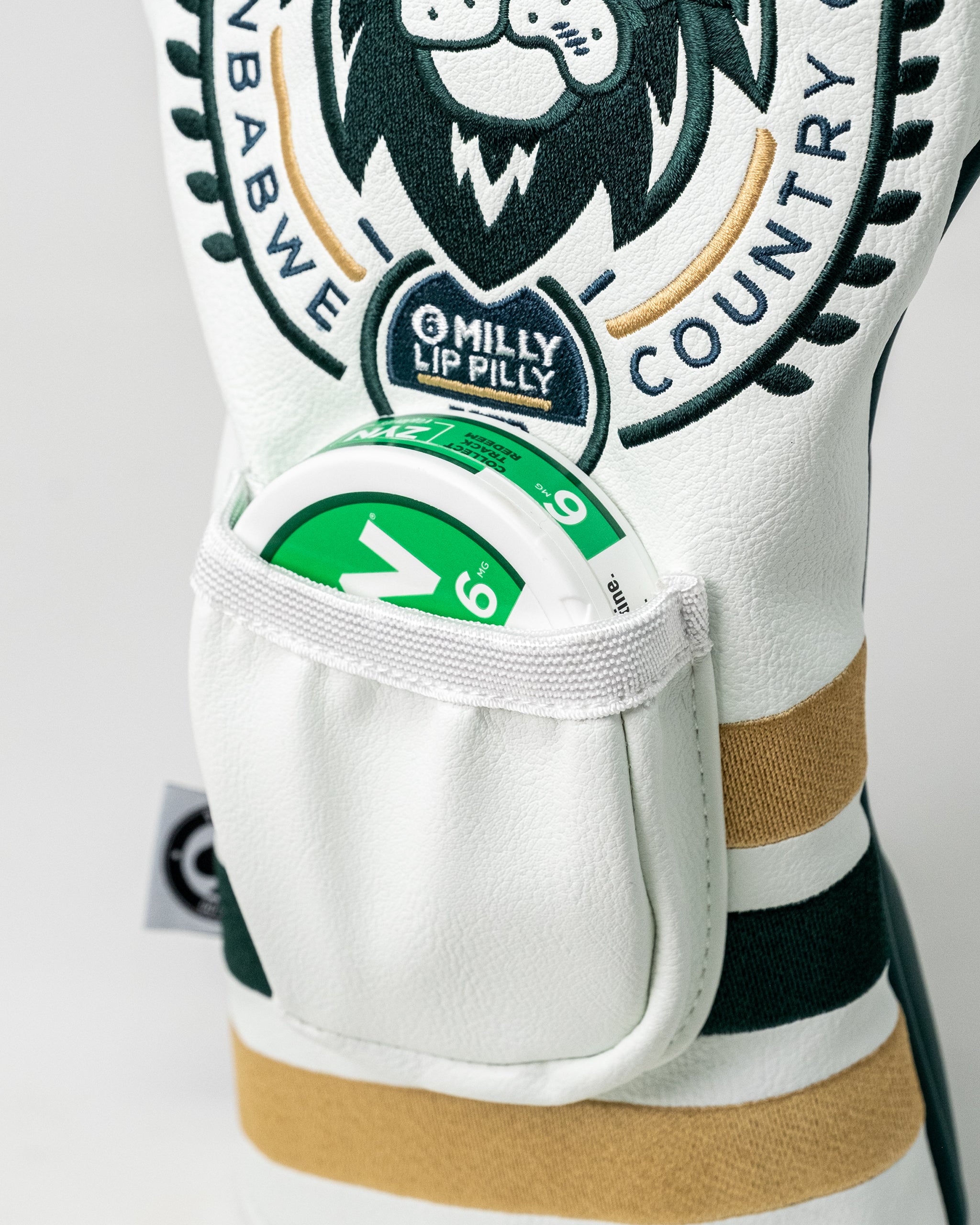 Close-up of a white golf glove with a branded patch, holding a green and white golf ball in a pocket, showcasing bold, spo...