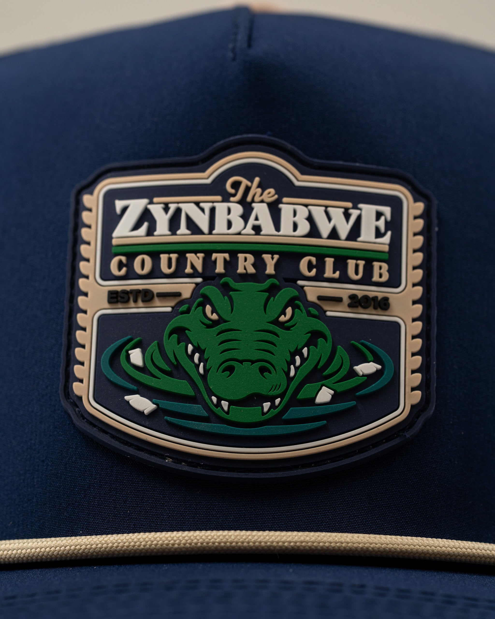 Navy perforated rope hat featuring a bold Zynbabwe Country Club logo with an alligator design. Ideal for stylish golfers.