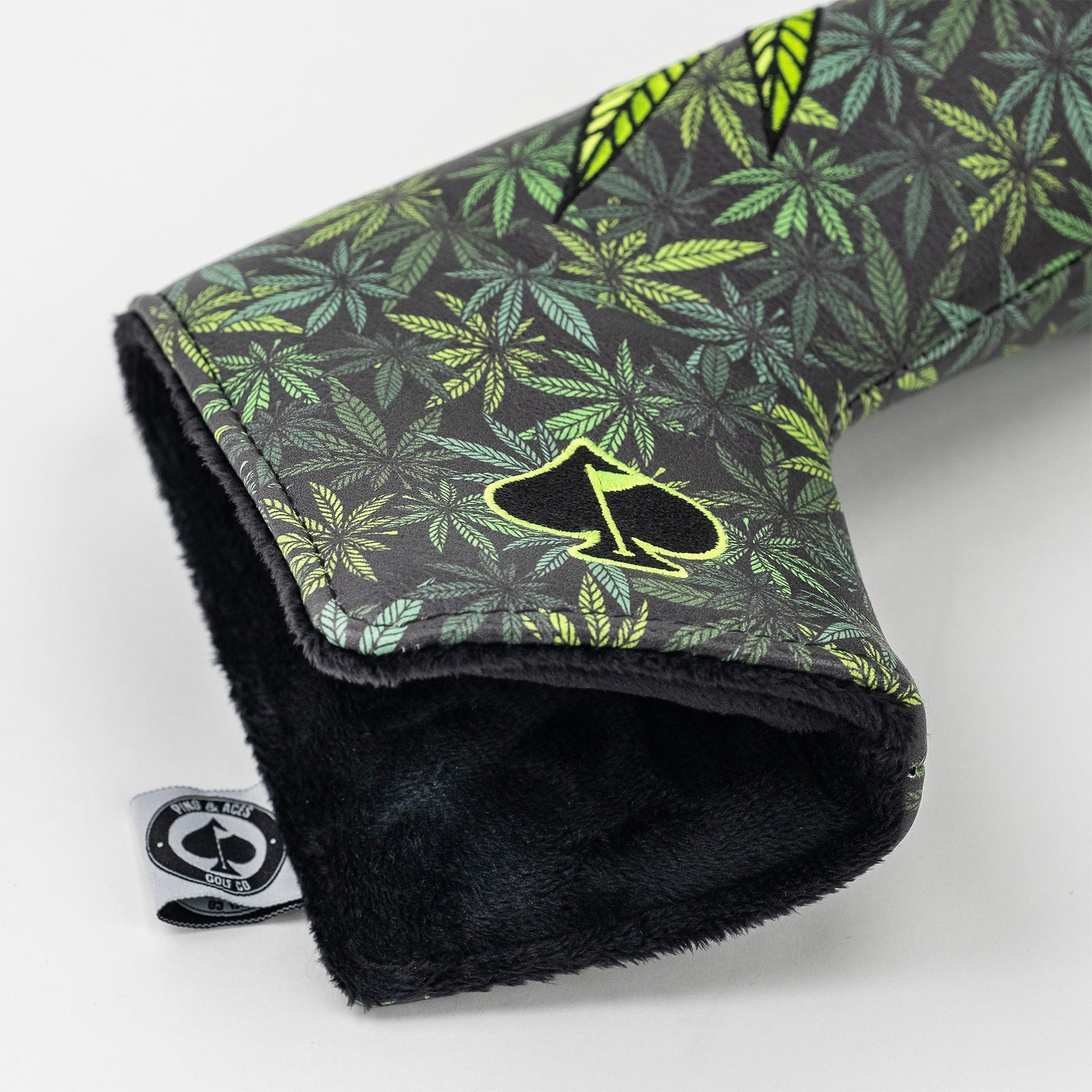 Colorful golf club headcover with green and black cannabis leaf pattern, embroidered logo, and plush black interior.