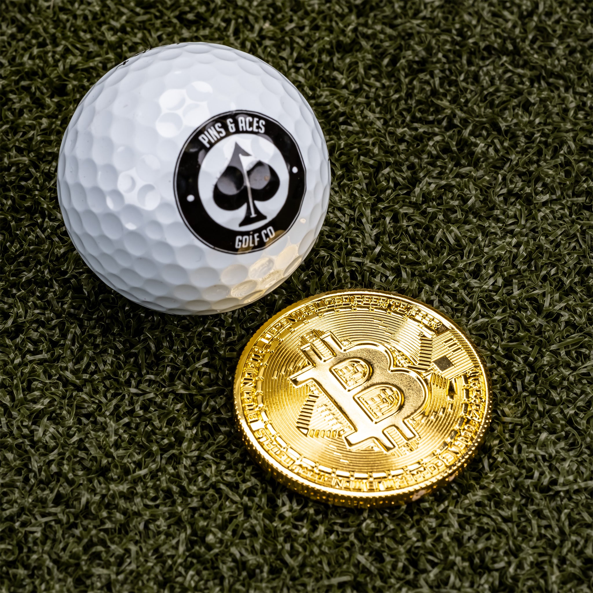 Bitcoin ball marker featuring the iconic Bitcoin logo, placed in front of a golf ball on a golf course background.