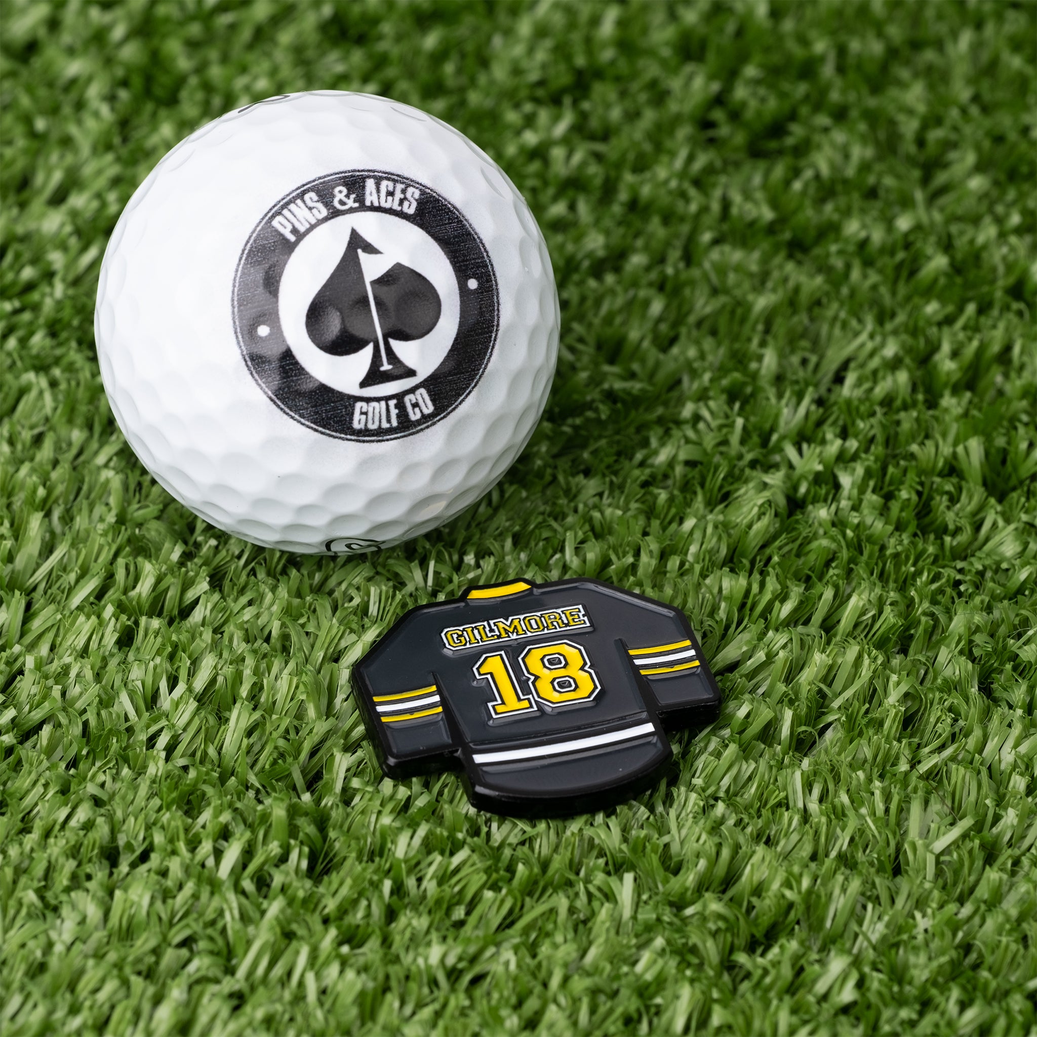 Gilmore Jersey Ball Marker beside a golf ball on a green surface.