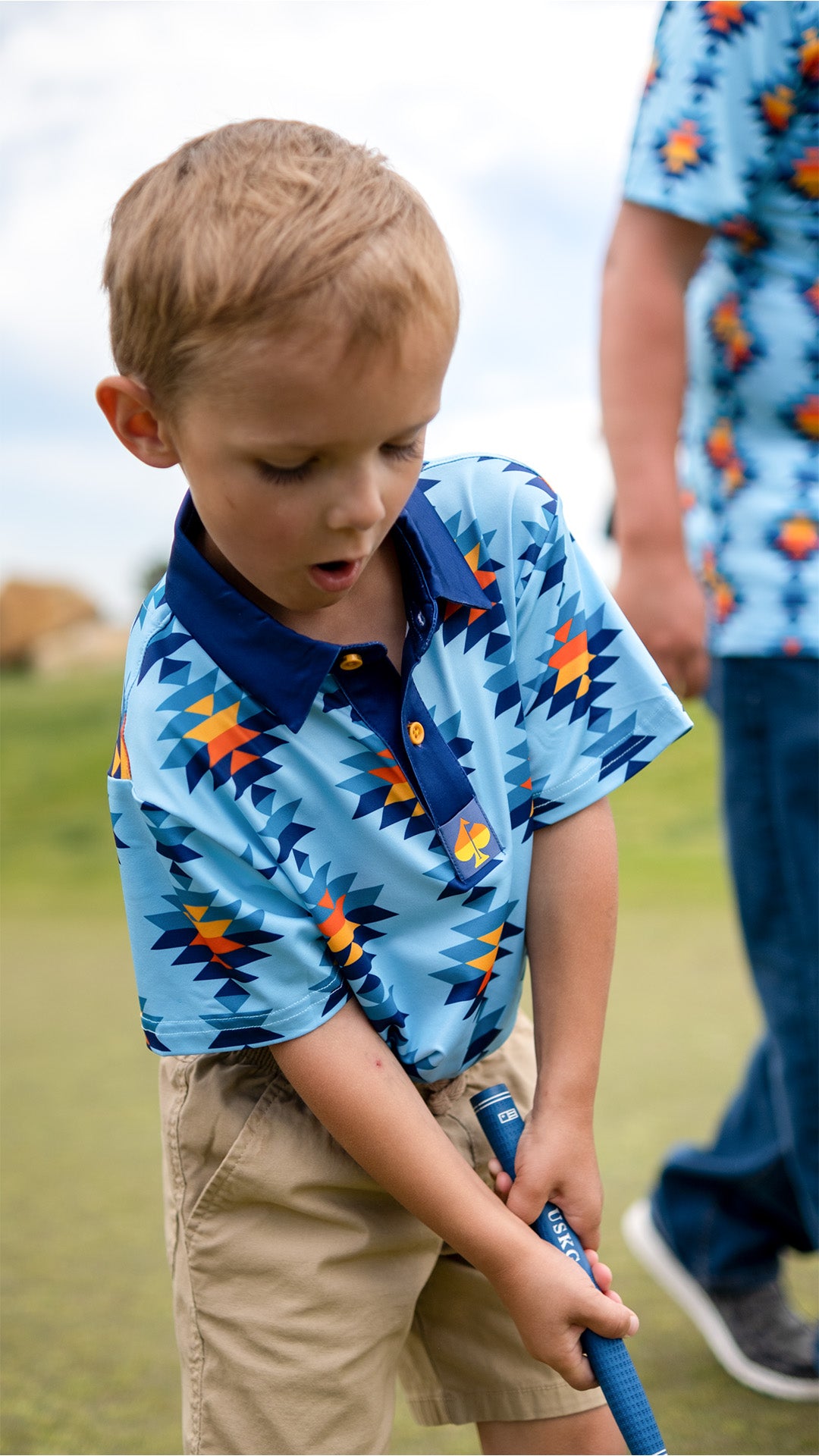 Youth Southwest Sunset Polo featuring vibrant sunset colors and a southwestern pattern, perfect for stylish kids.