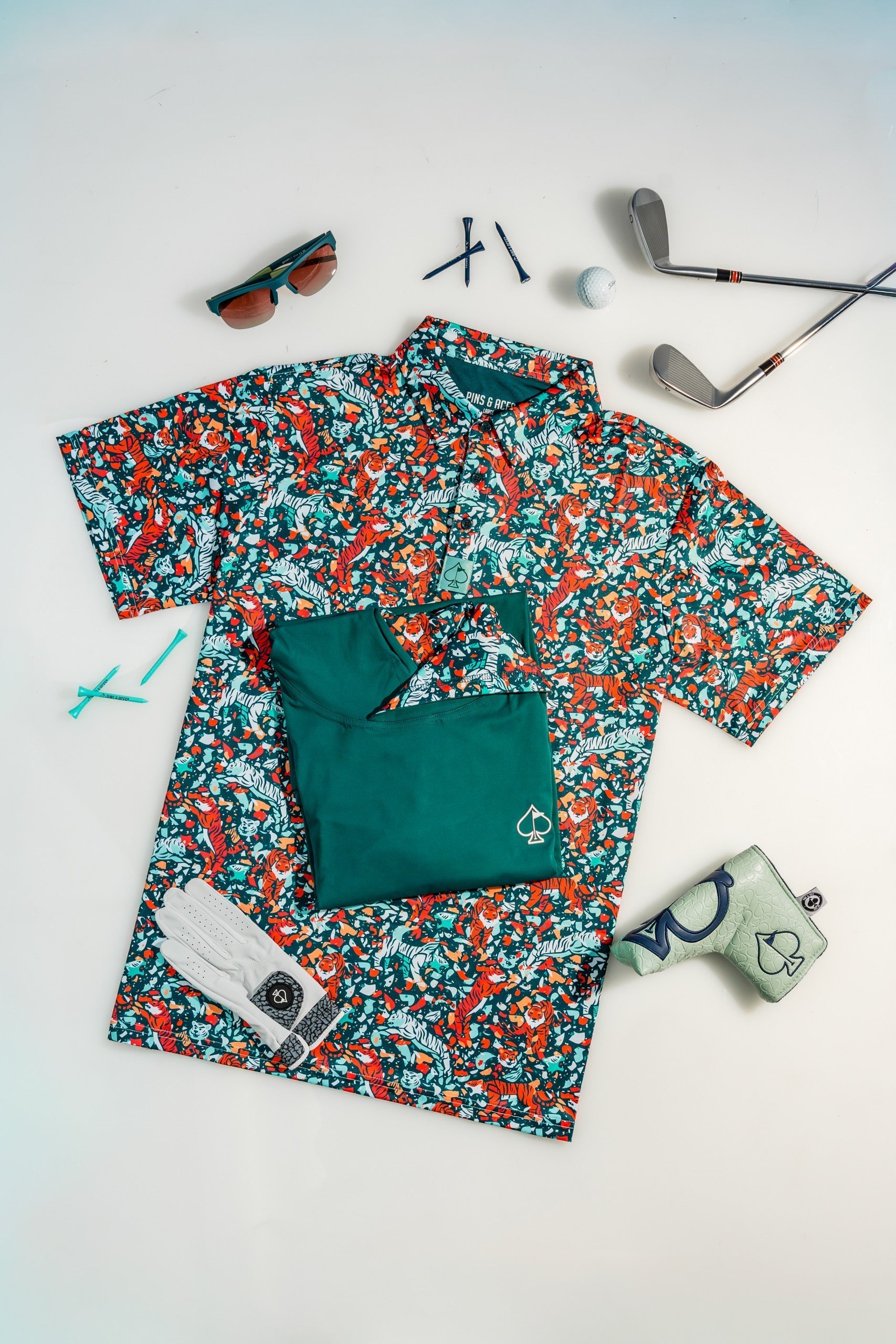 Golf gifts for dad 2026 — Pins & Aces polos, hoodies, headcovers and gloves flatlay