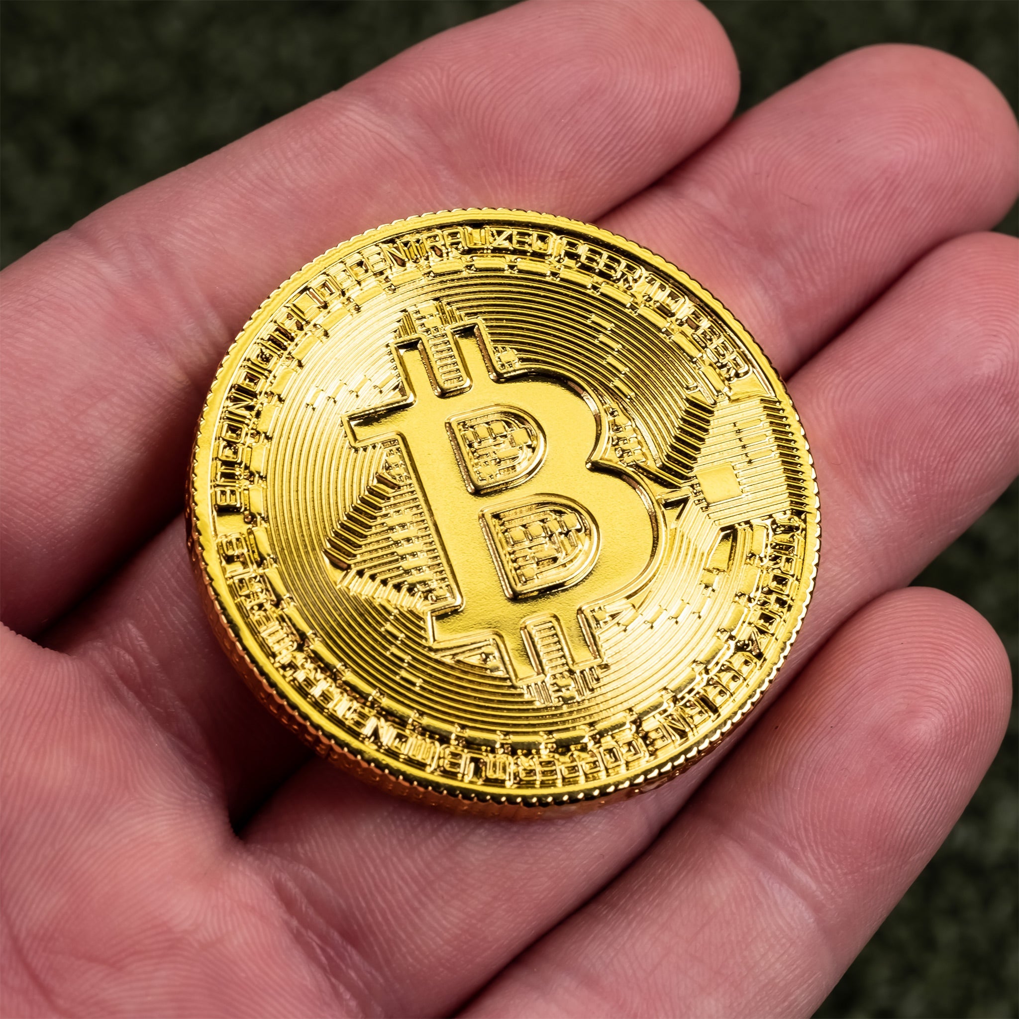 Gold Bitcoin ball marker held in a hand, featuring intricate detailing and the iconic Bitcoin logo for golfers.