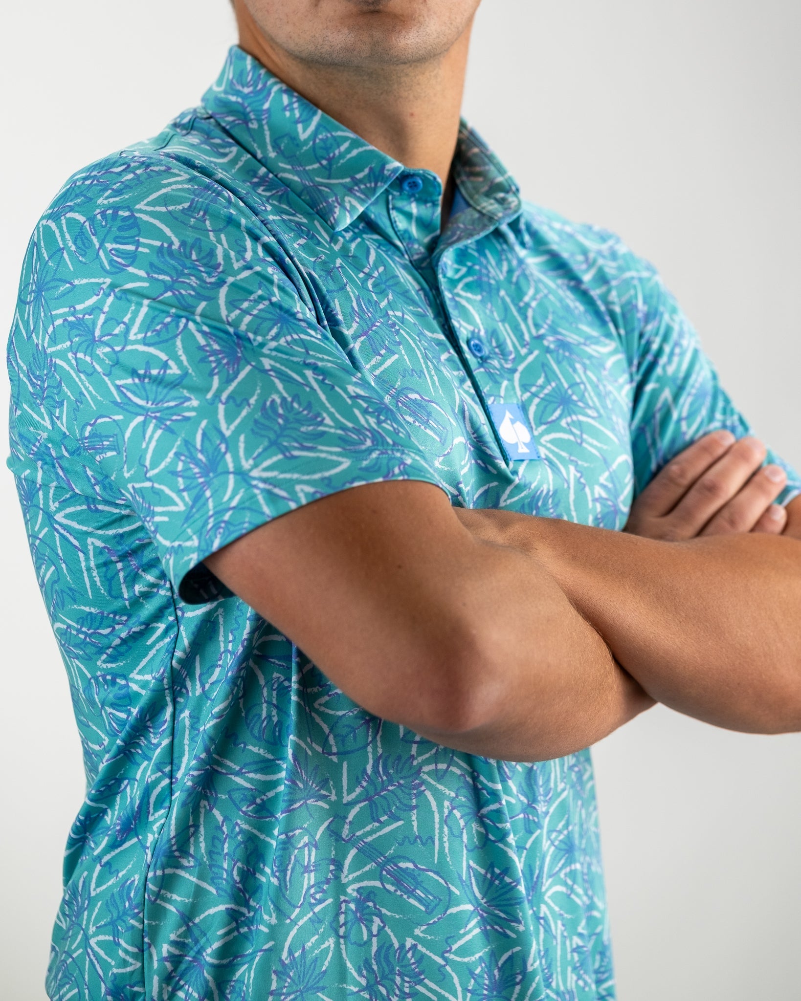 Men's Margaritaville 5 O'Clock Ocean polo shirt featuring a vibrant tropical leaf pattern in shades of blue and green.