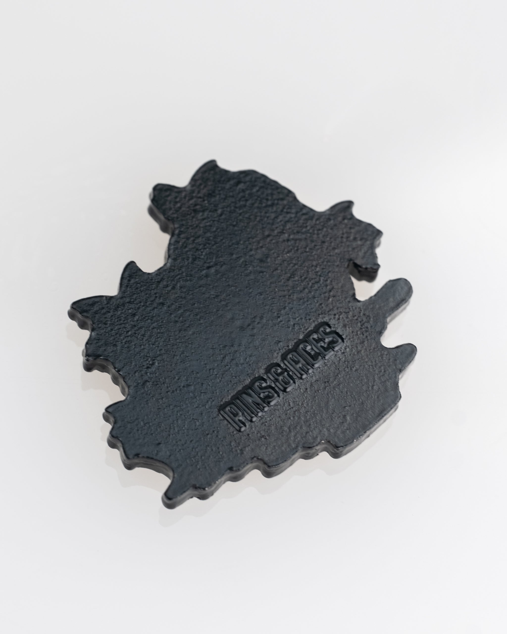 Black ball marker shaped like a parrot, featuring a textured design and the Pins and Aces logo for golfers.