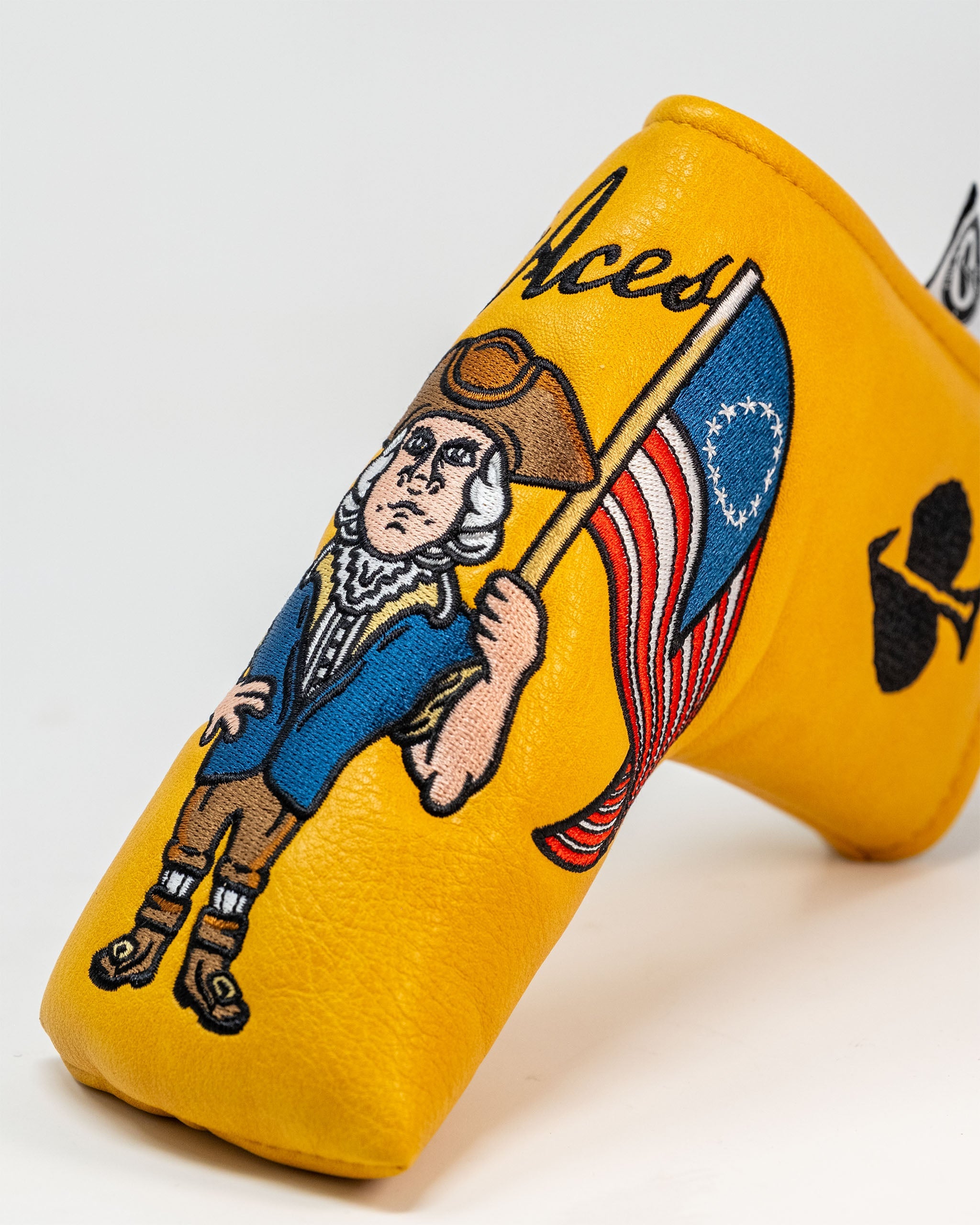 Bold yellow putter cover featuring a patriotic design with a historical figure holding an American flag and the Pins and Aces logo.