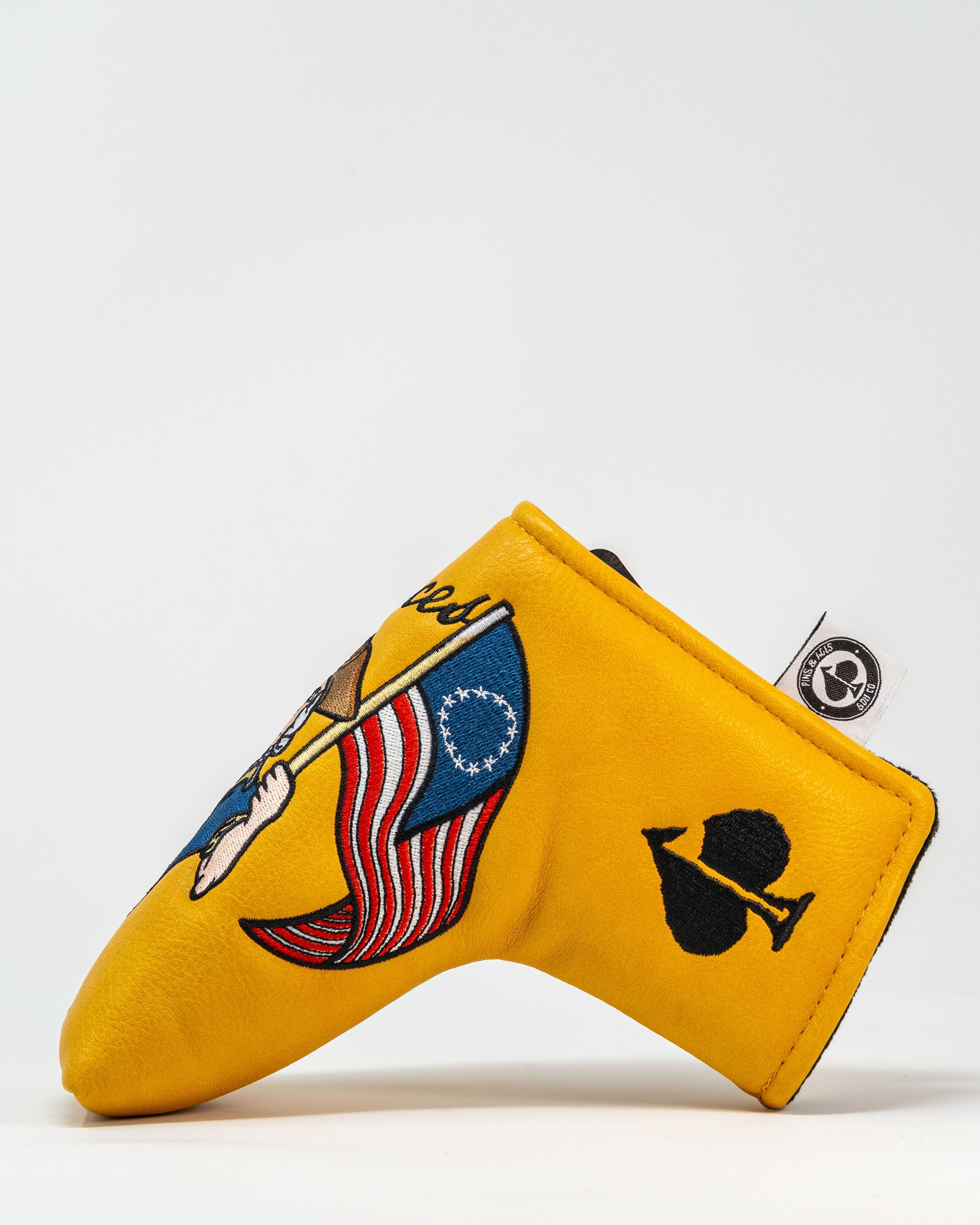 Bold yellow putter cover featuring patriotic designs, including an American flag and a unique emblem, perfect for golfers.