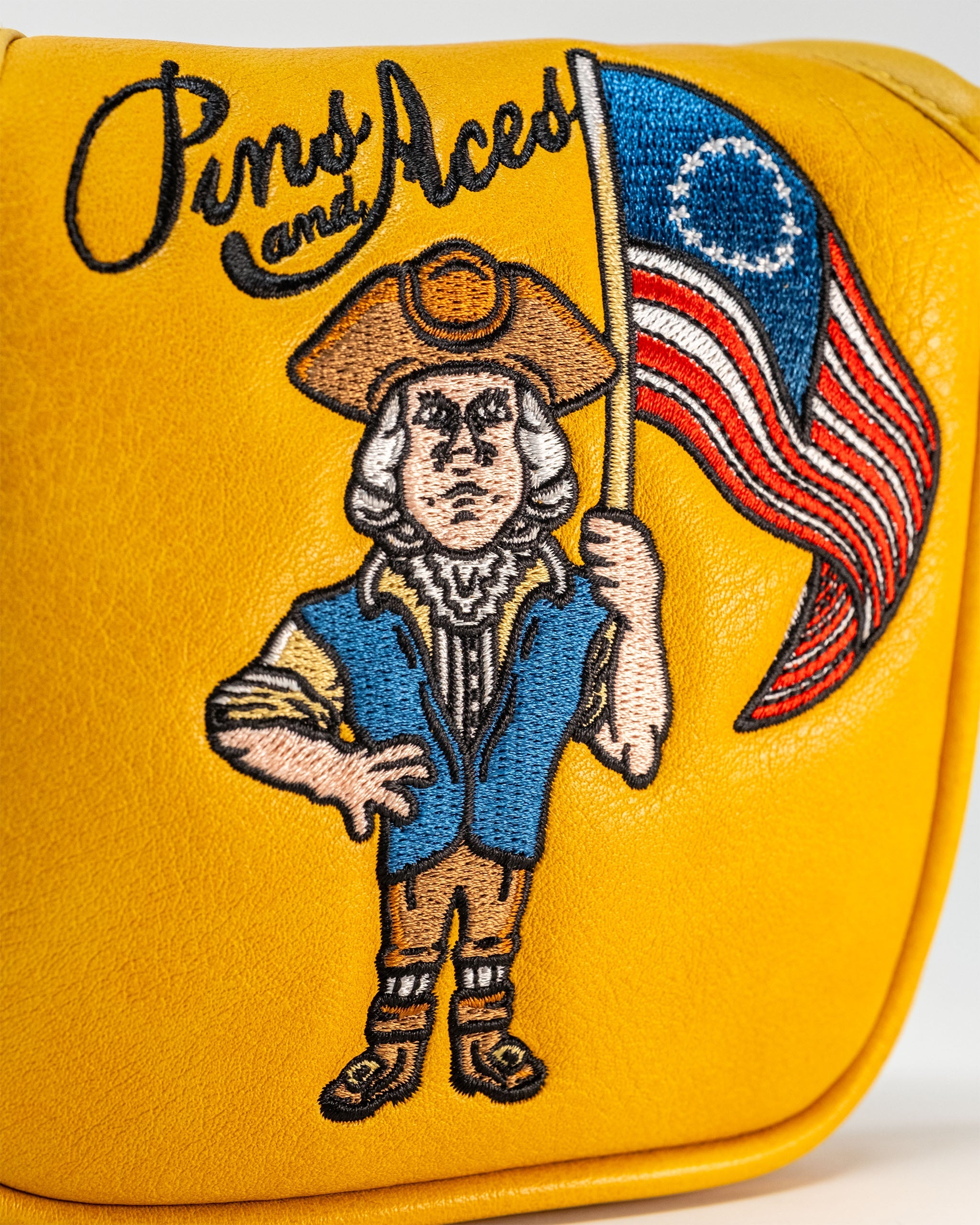 Bold yellow mallet cover featuring a patriotic character holding an American flag, showcasing Pins and Aces branding.