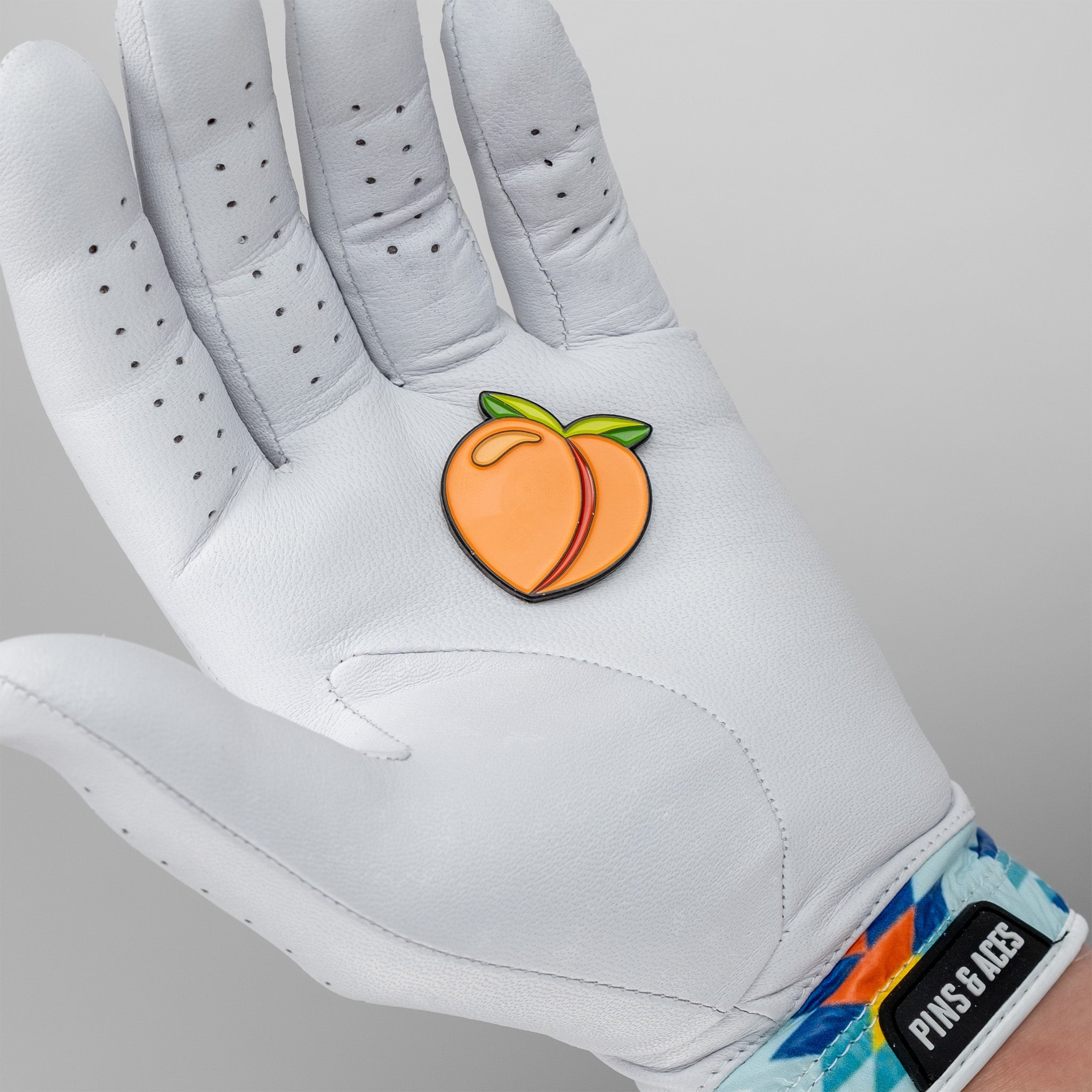 Peach ball marker resting on a golfer's gloved hand, showcasing its vibrant design and smooth finish.