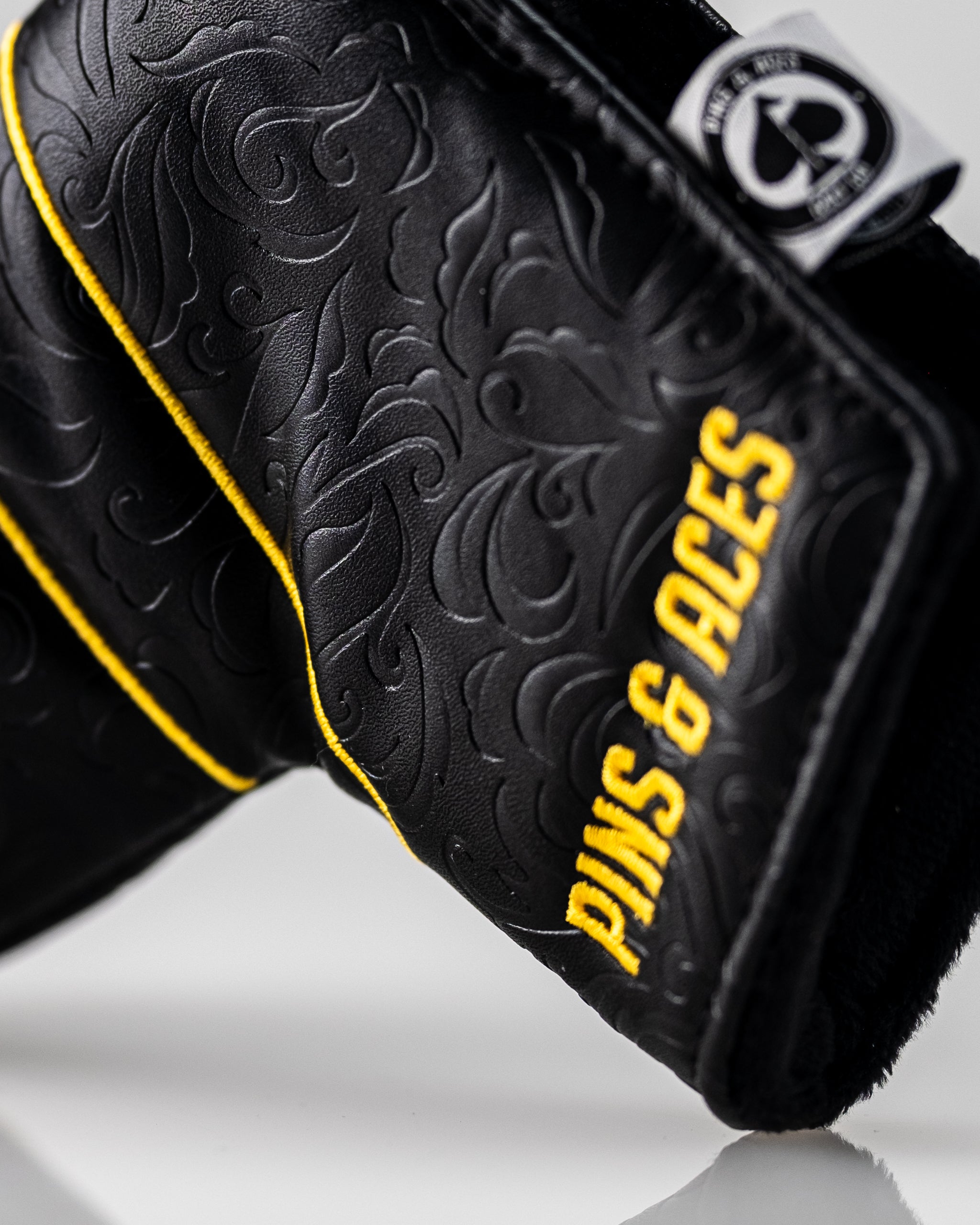 Black and gold Ace of Spades blade putter cover featuring intricate designs and bold lettering from Pins and Aces.