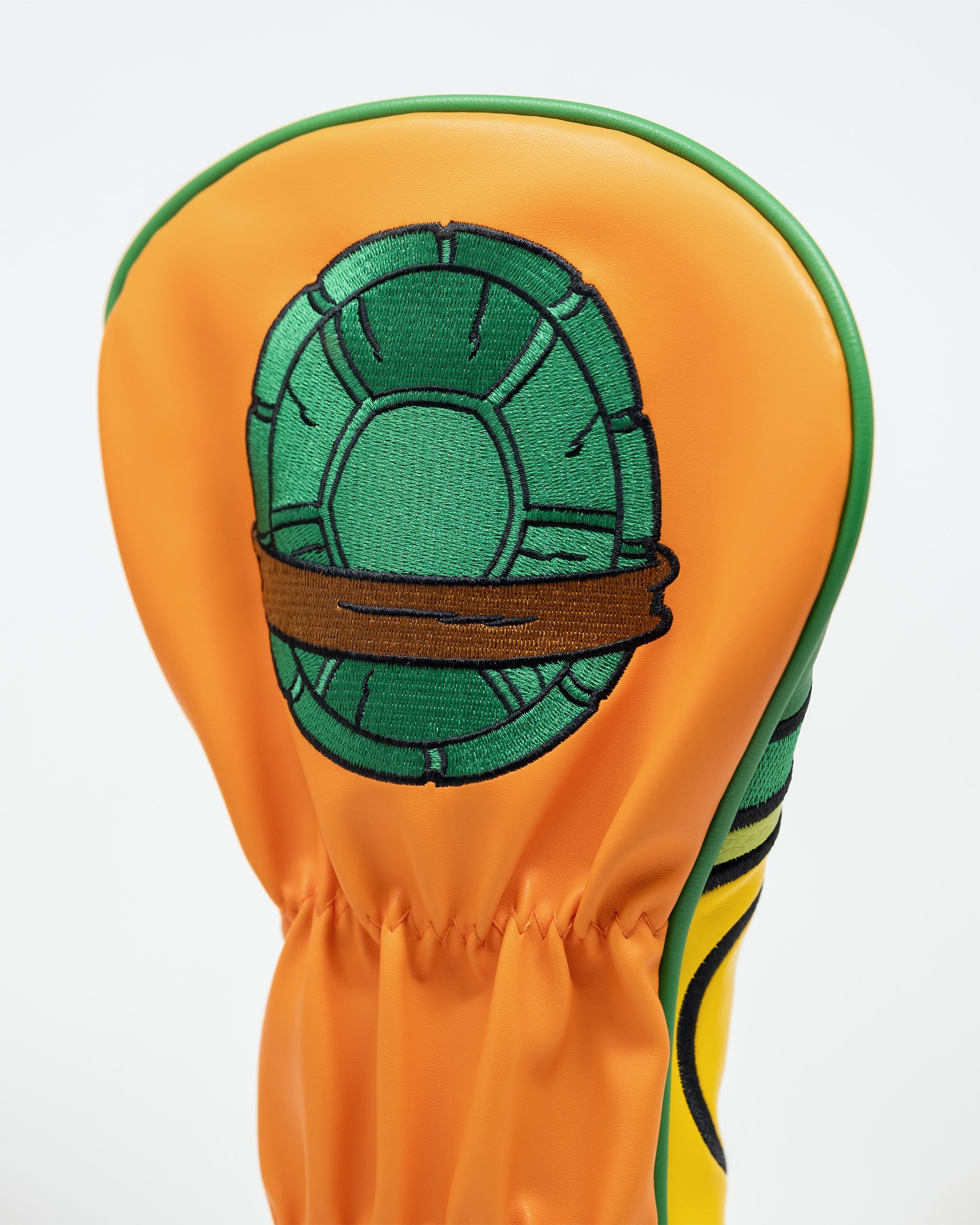Michelangelo-themed golf driver cover featuring a vibrant orange design with a turtle shell graphic.