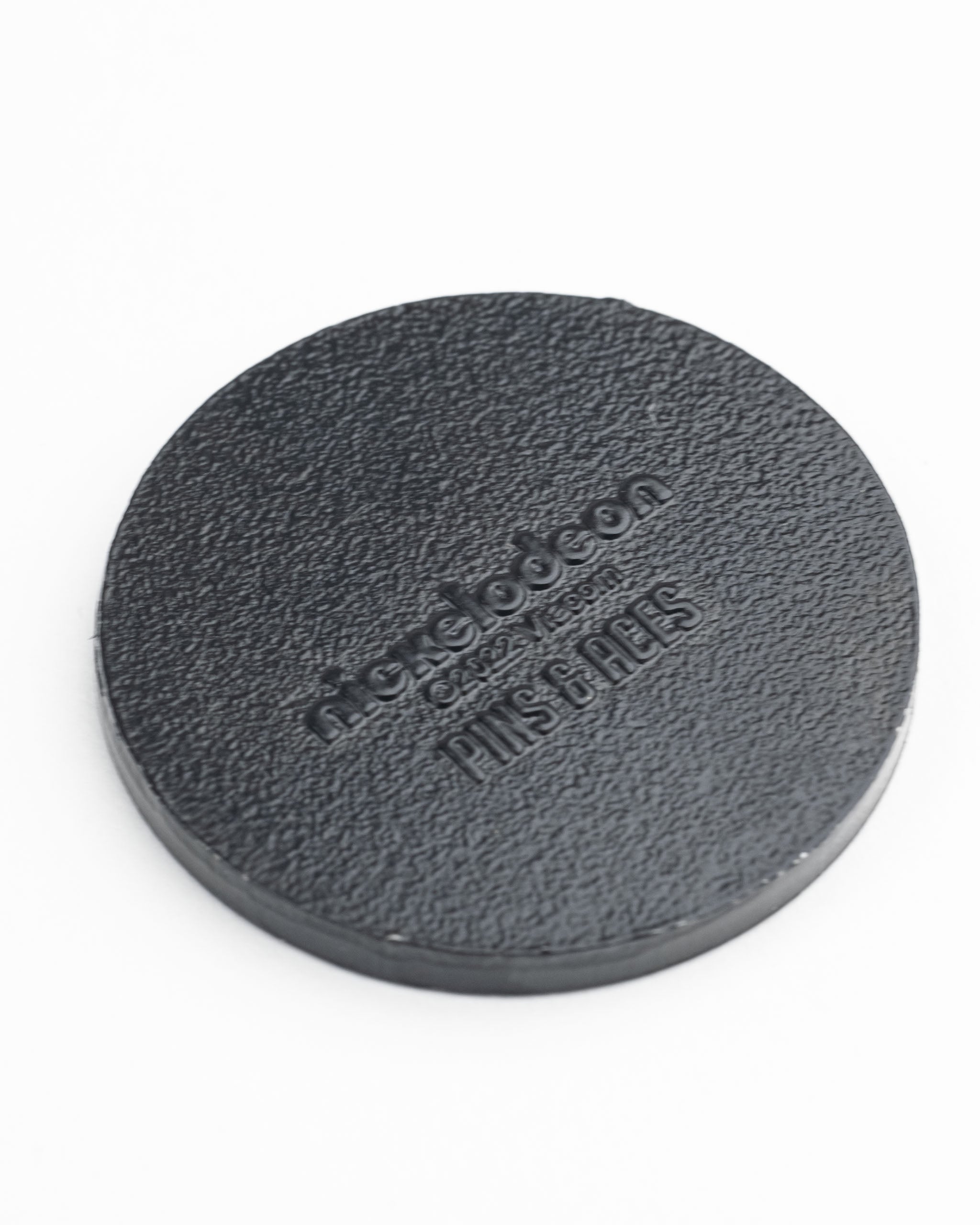 TMNT sewer cover ball marker featuring a textured black design with the Nickelodeon logo, ideal for golf enthusiasts.