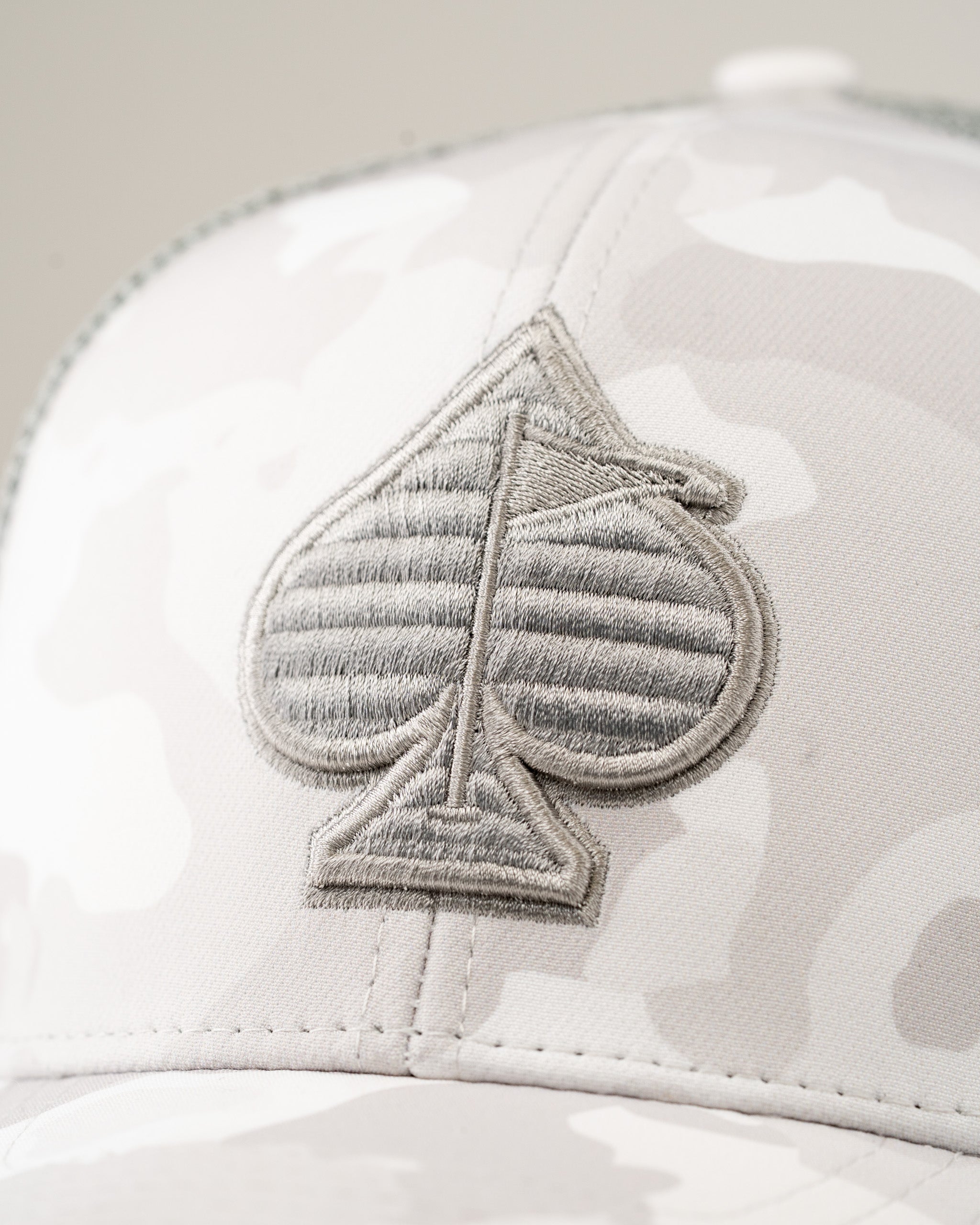 Trucker hat in Arctic Camo featuring a textured gray spade logo, perfect for stylish golfers on the course.