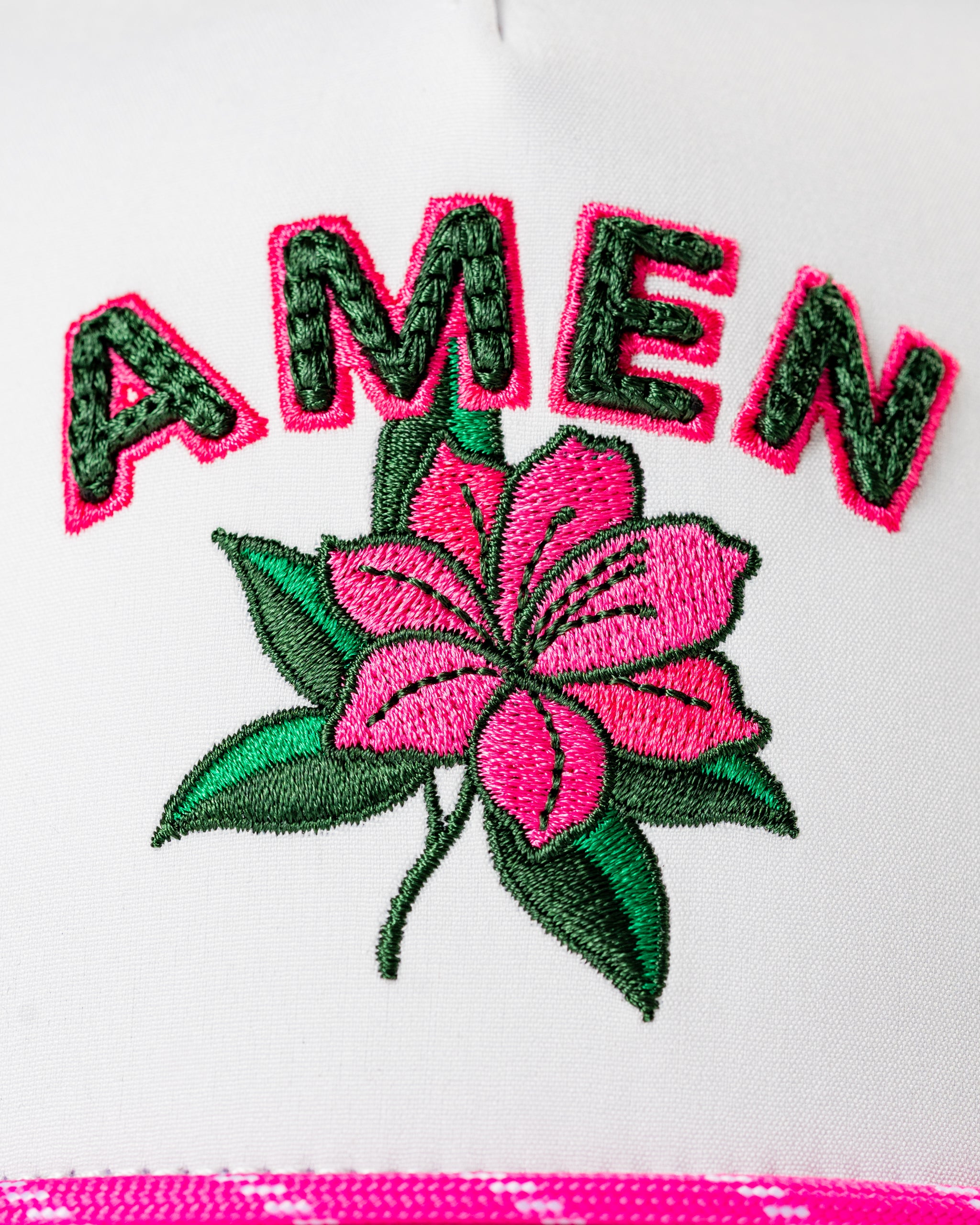 White perforated rope hat featuring vibrant pink "AMEN" embroidery and a floral design, perfect for stylish golfers.