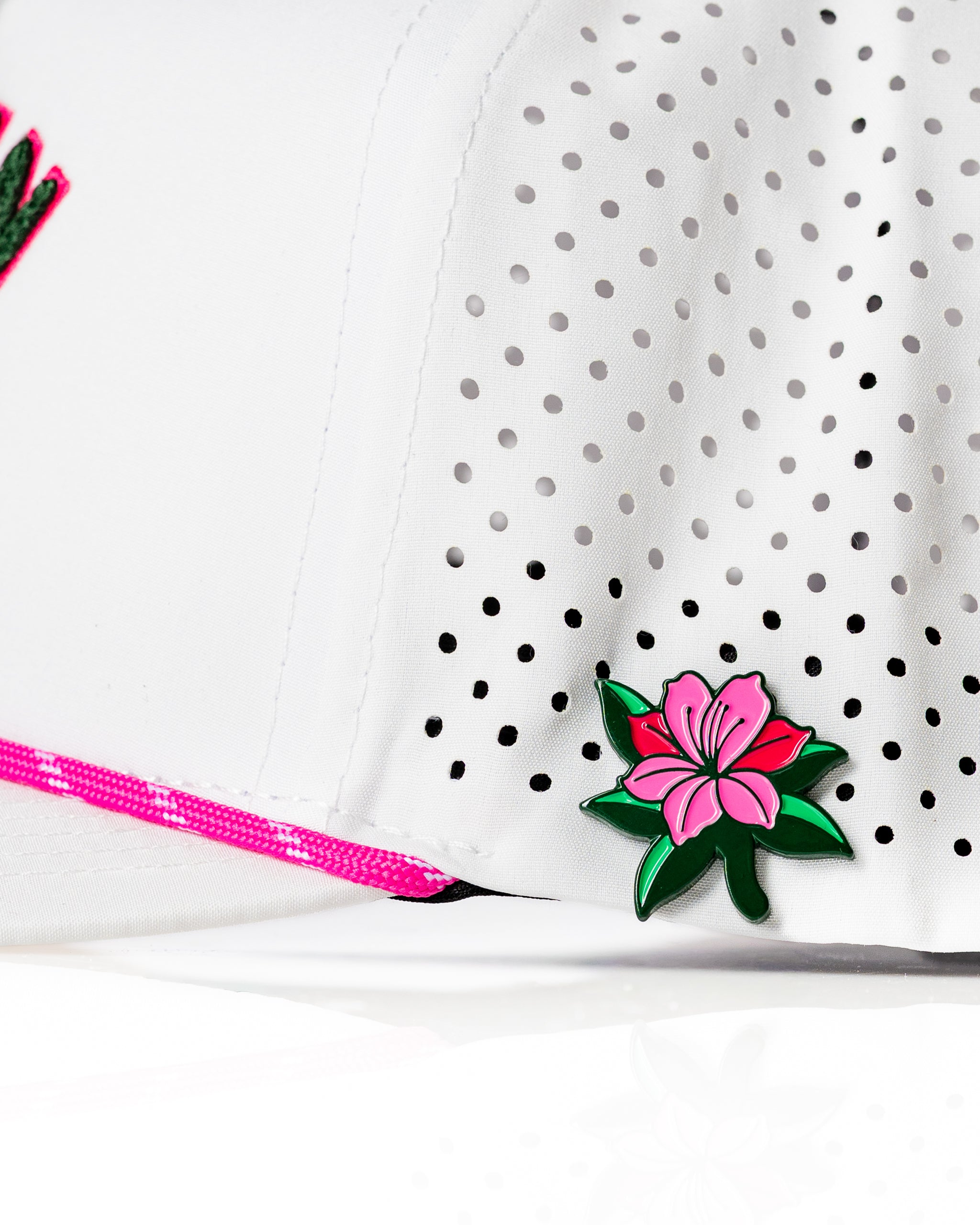 Perforated white rope hat featuring a pink azalea flower emblem, perfect for stylish golfers seeking standout accessories.