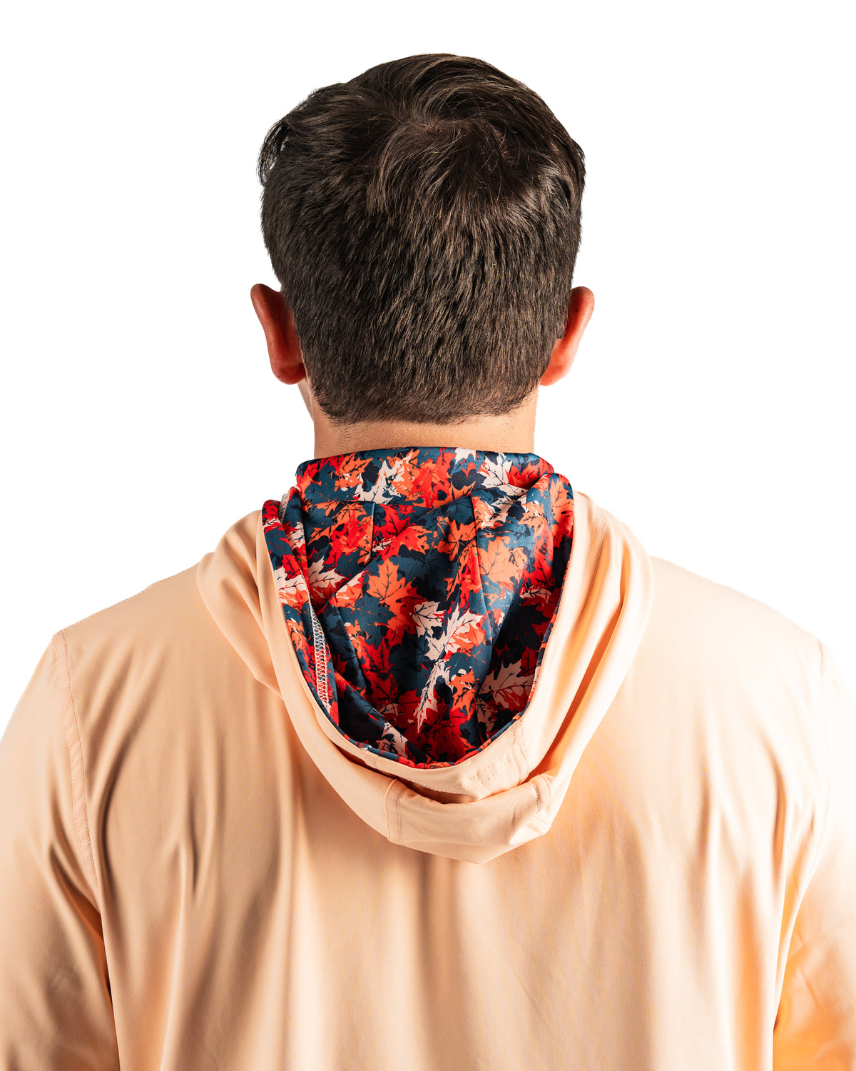 Men's performance golf hoodie in soft peach with a vibrant autumn leaves patterned hood, designed for comfort on the course.